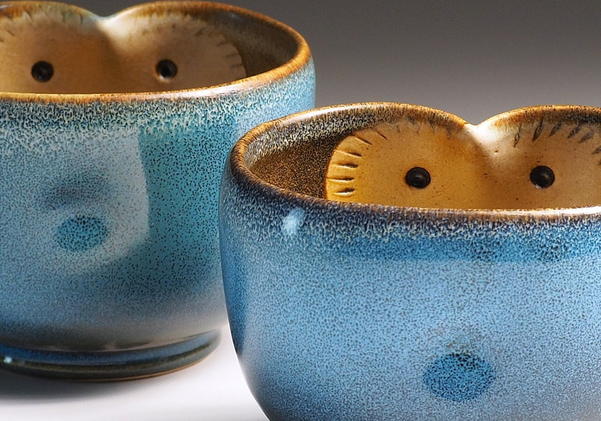 Detail of two blue Japanese teacup with a owl design on a gradient background