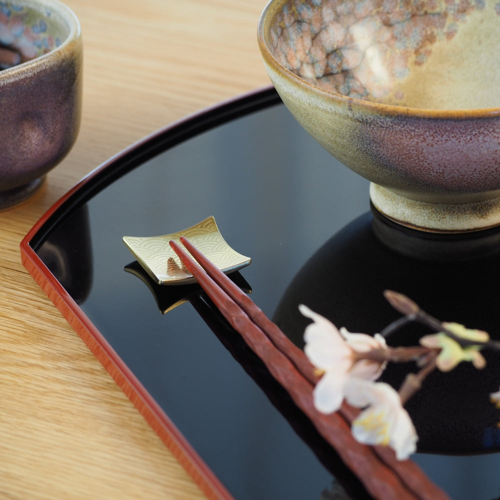 Japanese ceramic bowls and black tray with chopsticks on a wooden surface. Tsukushi