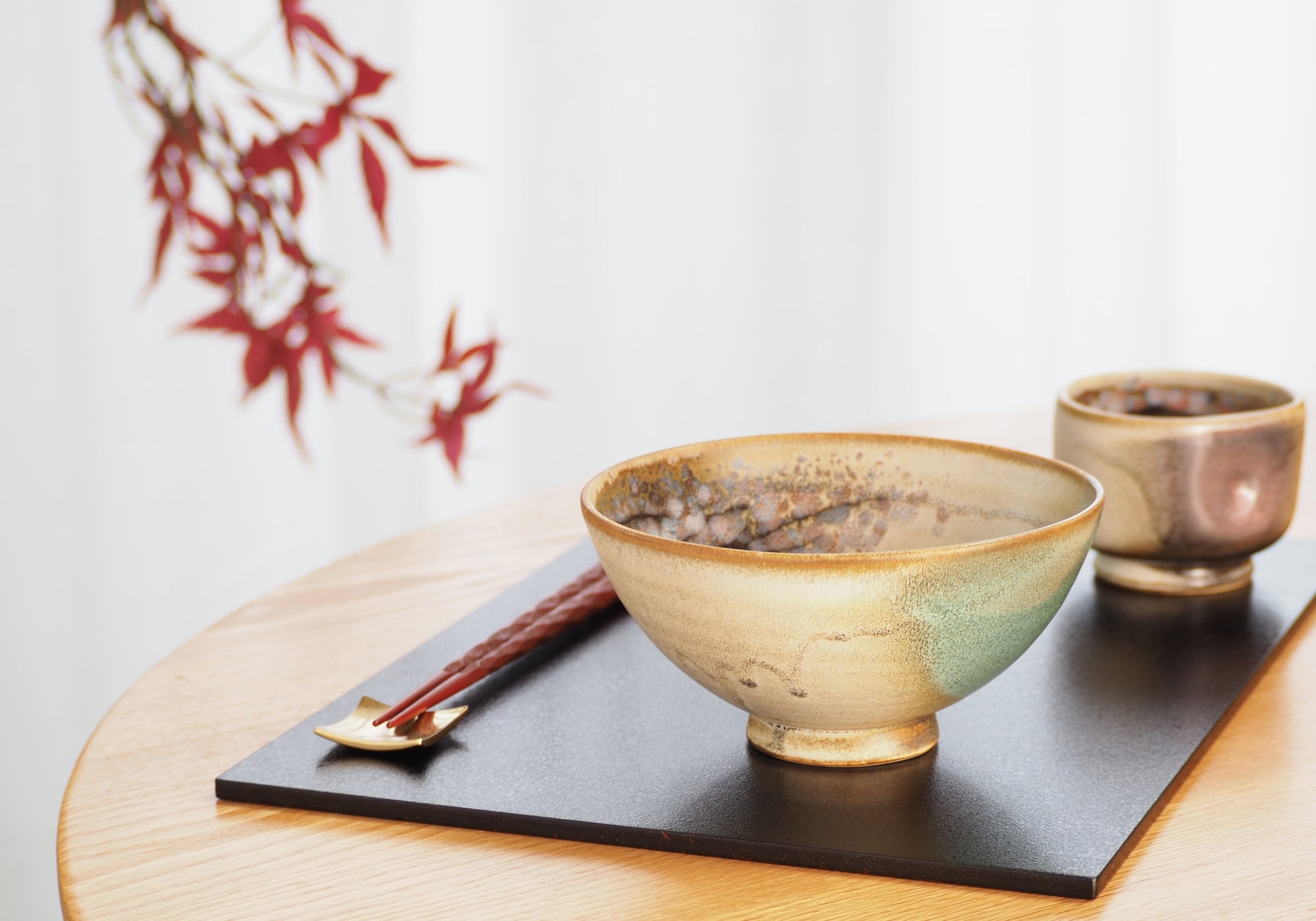 A Japanese ceramic bowl and a teacup on a wooden surface. Tsukushi