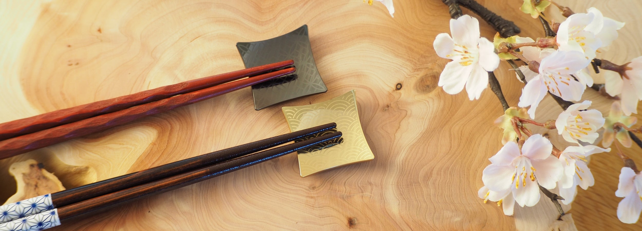 Gold and Black Chopstick rests on wooden table.