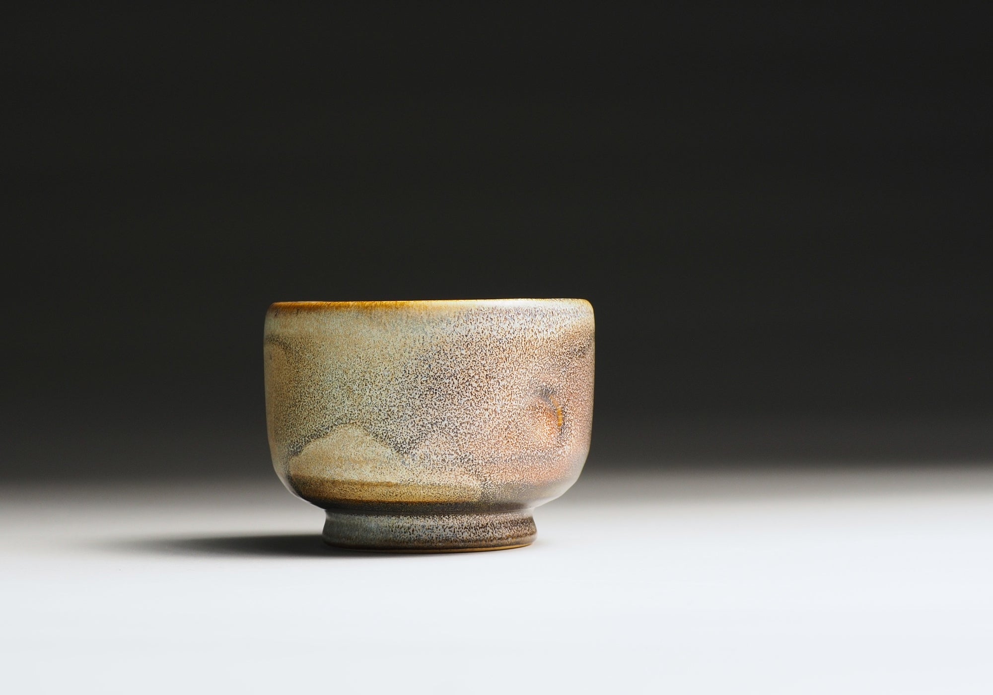 Japanese ceramic teacup with a textured surface on a dark background.