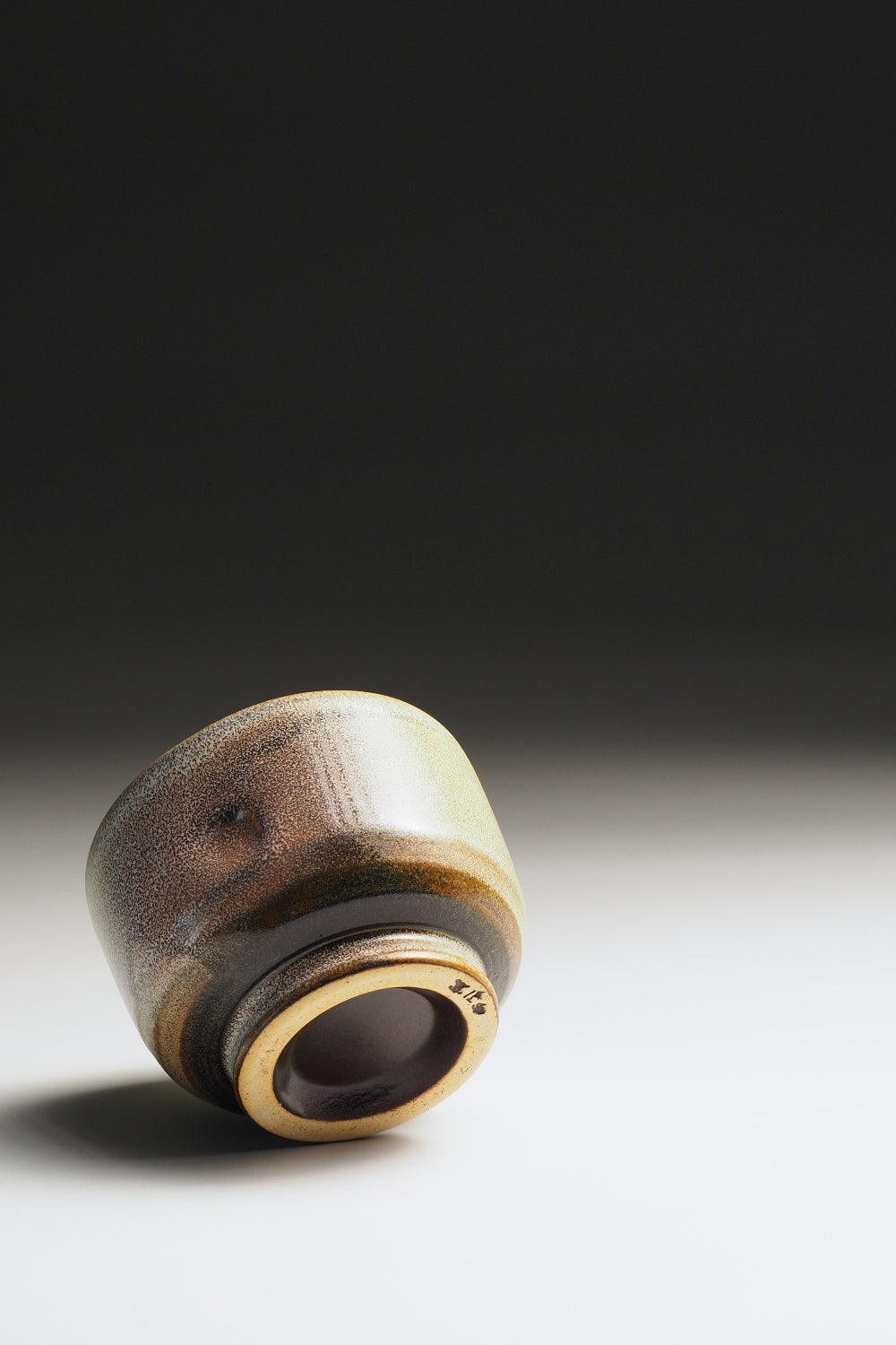 Bottom view of a Japanese pottery teacup with a pink and brown gradient finish