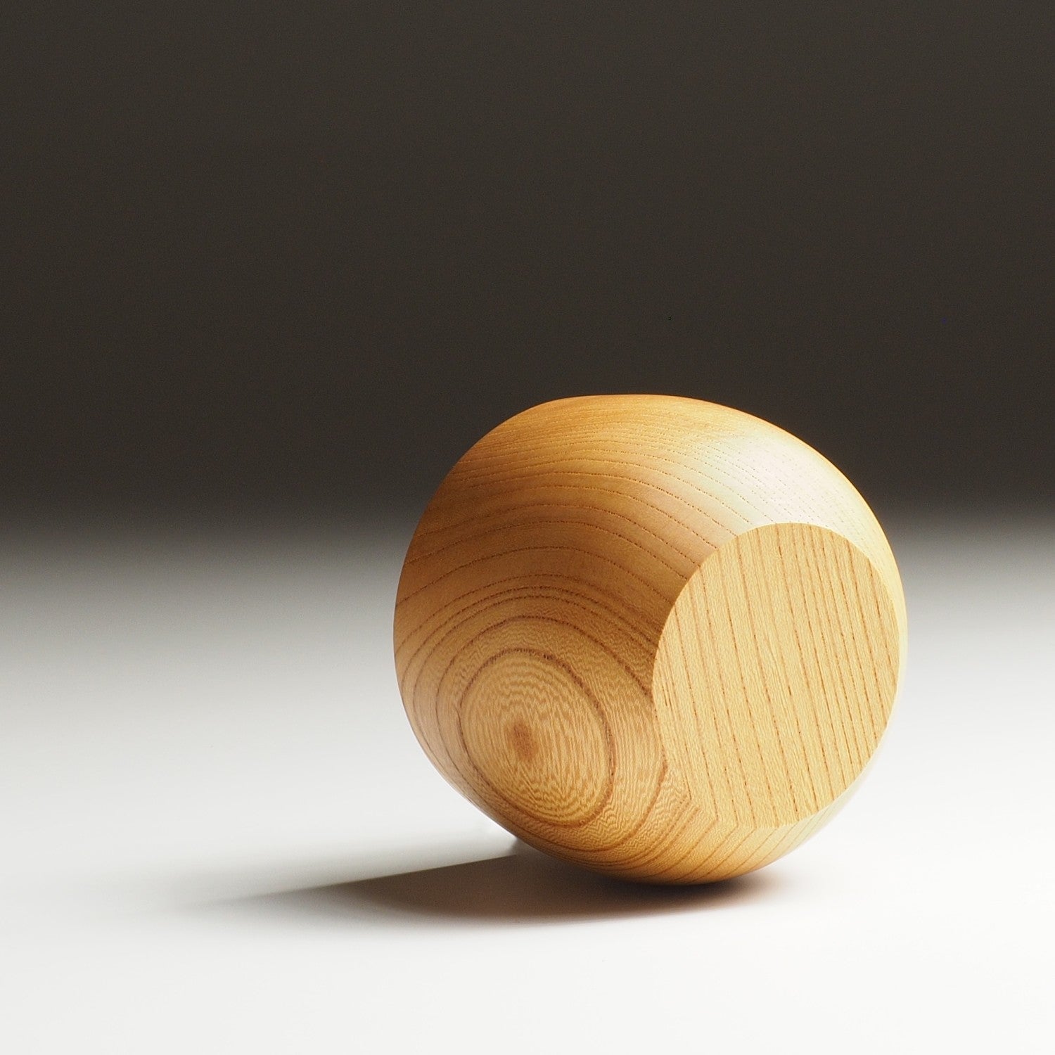 A back side view of a Japanese wooden yunomi cup on a gradient background. Tsukushi