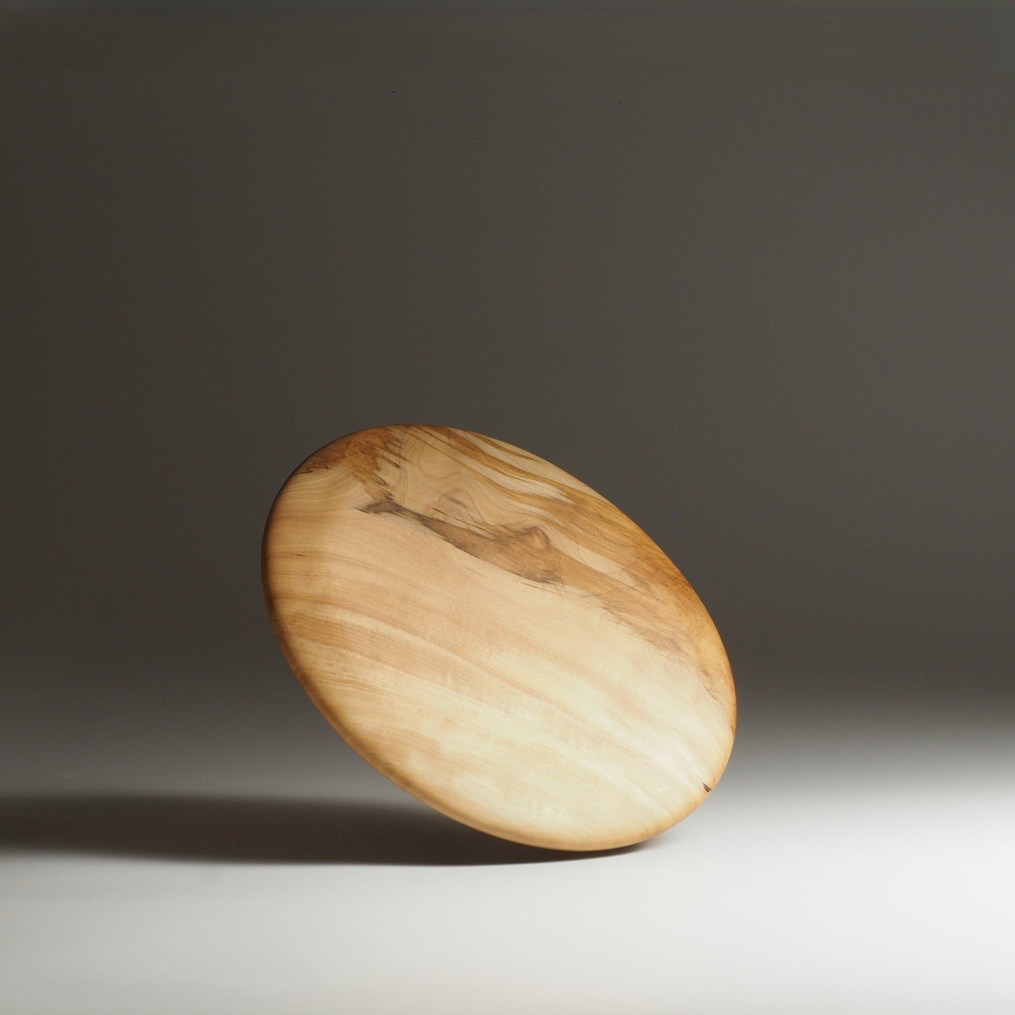 A backside view of a Japanese wooden dinner plate on a beige background. Tsukushi