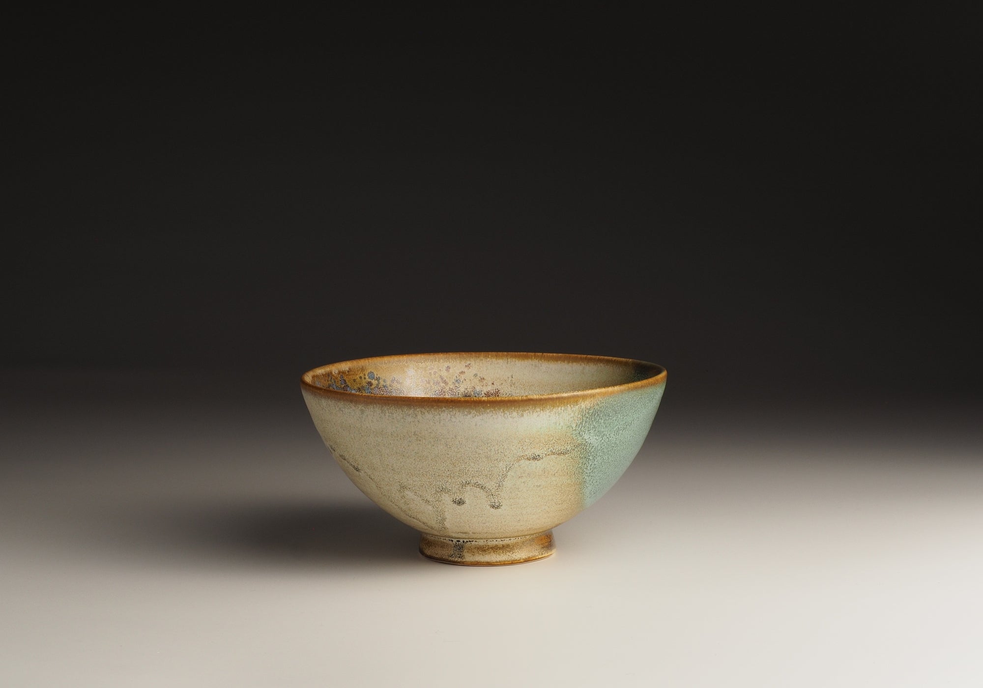 A Japanese ceramic bowl with green accent on a neutral background. Tsukushi