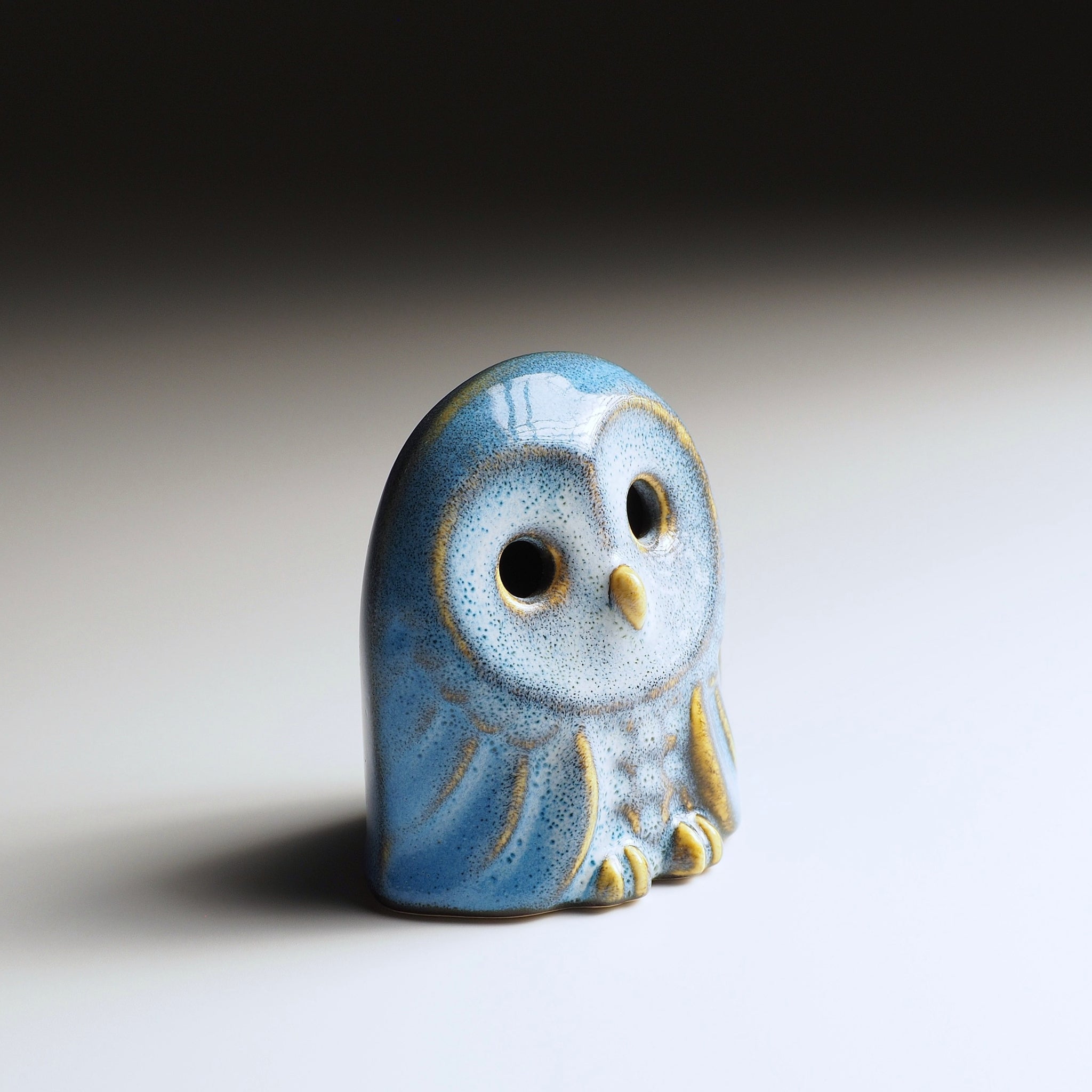 Oblique view of Engifuku owl figurine by Kazuhiro Kojima, blue speckled ceramic glaze, golden accents, dark eyes, gradient background.