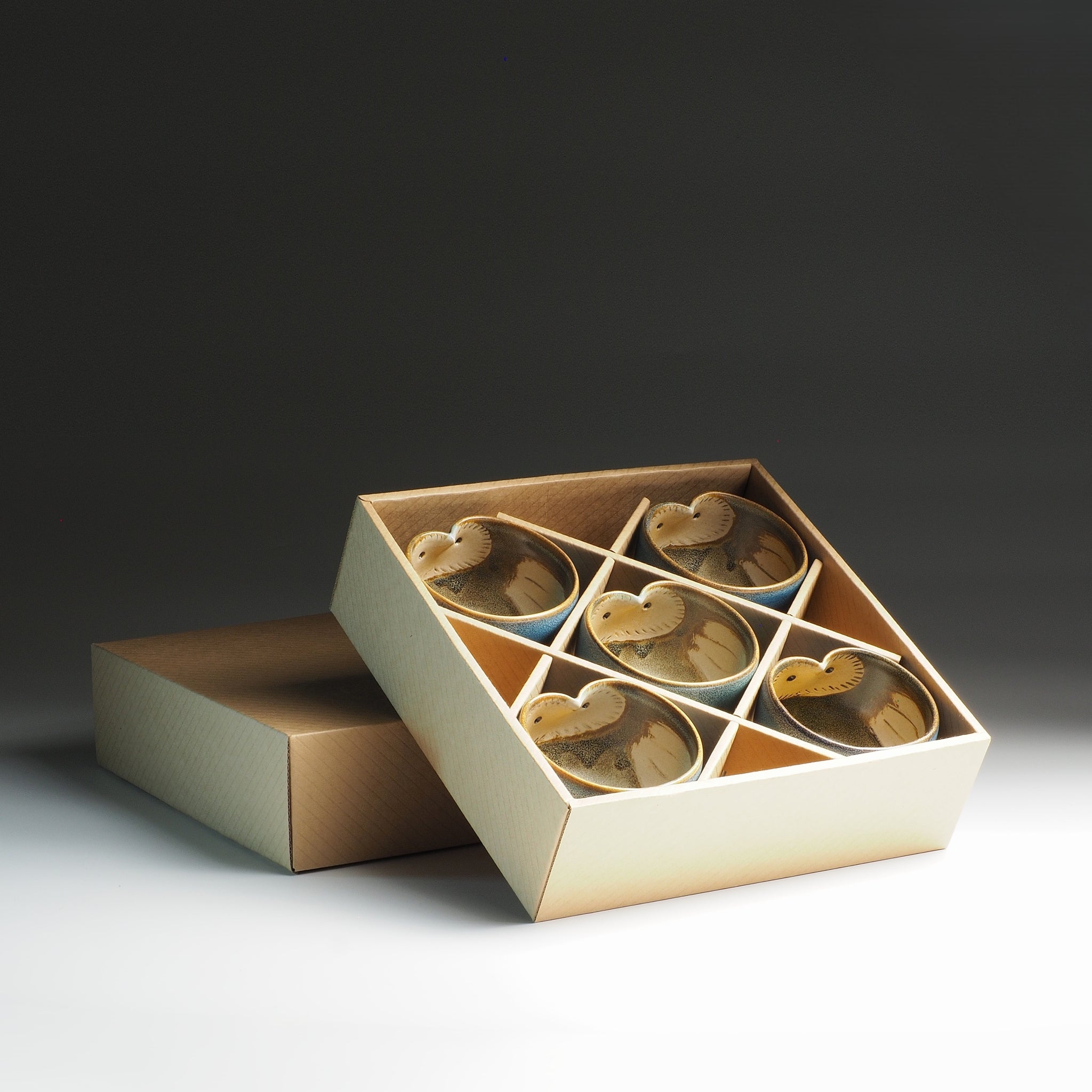 Open cardboard box with five owl-themed Japanese teacups inside.