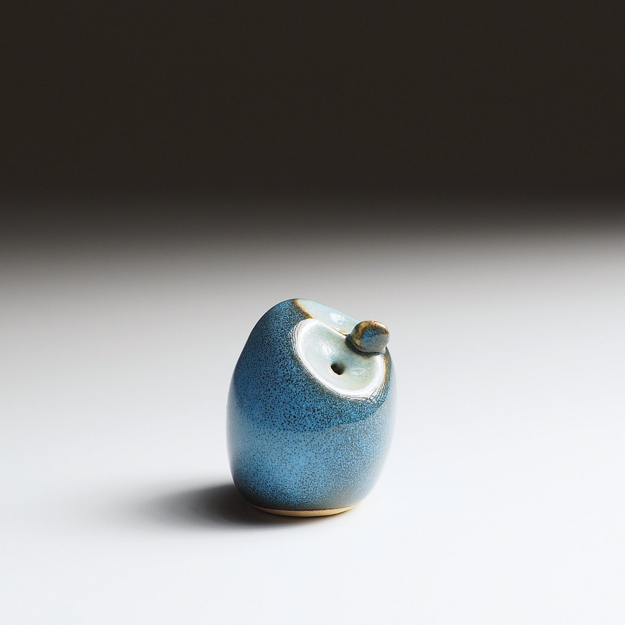 Twilight blue Gofuku ceramic owl figurine, side view showing rounded silhouette and textured Nanasai Tenmoku glaze finish.