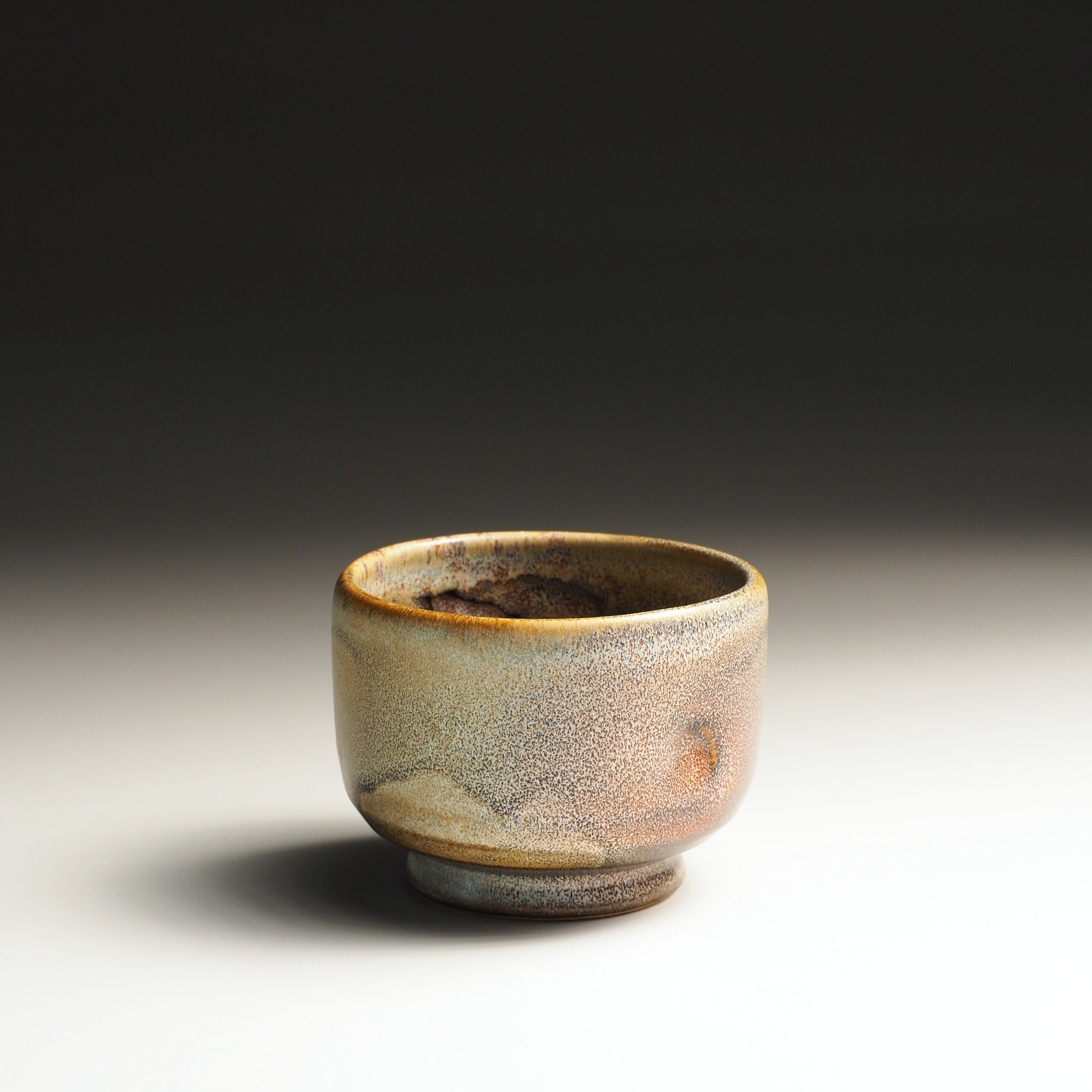 Japanese pottery yunomi cup with a textured surface on a gradient background