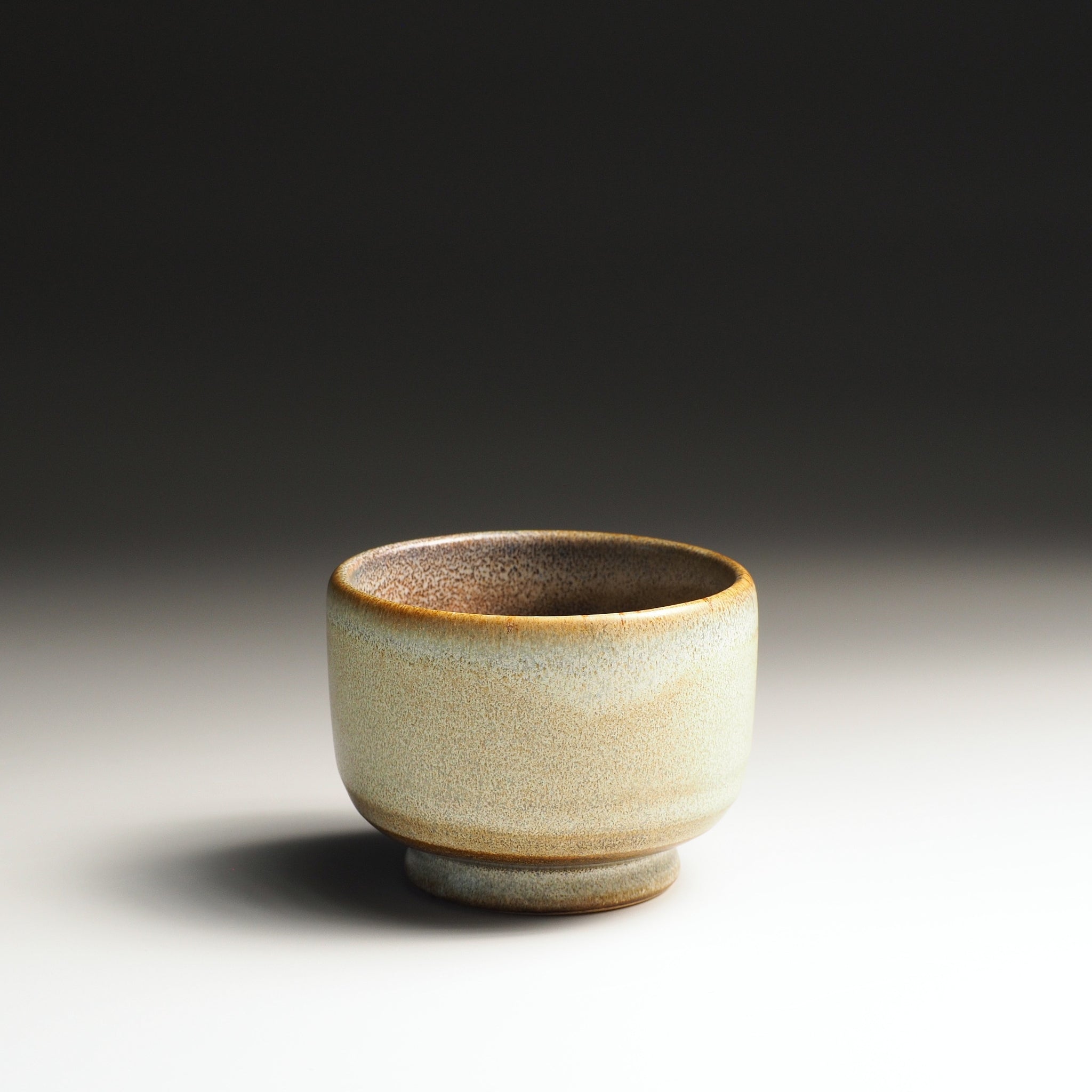 Pottery yunomi cup with a textured surface on a gradient background
