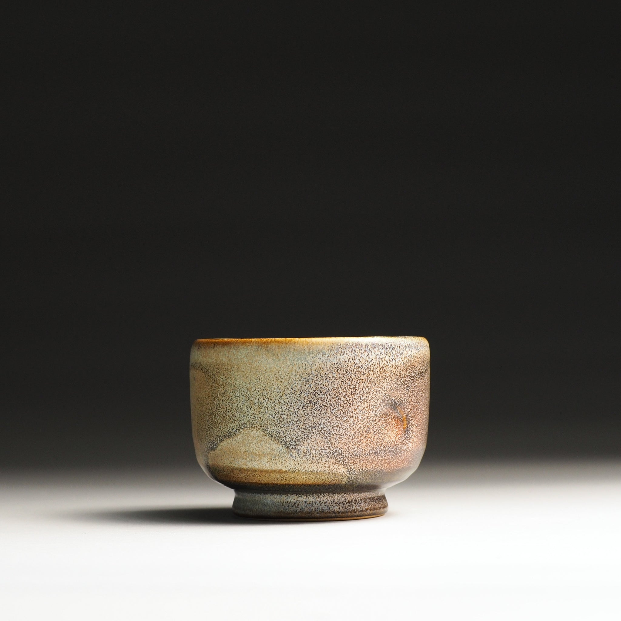 front view of a pottery teacup with a textured surface on a dark background