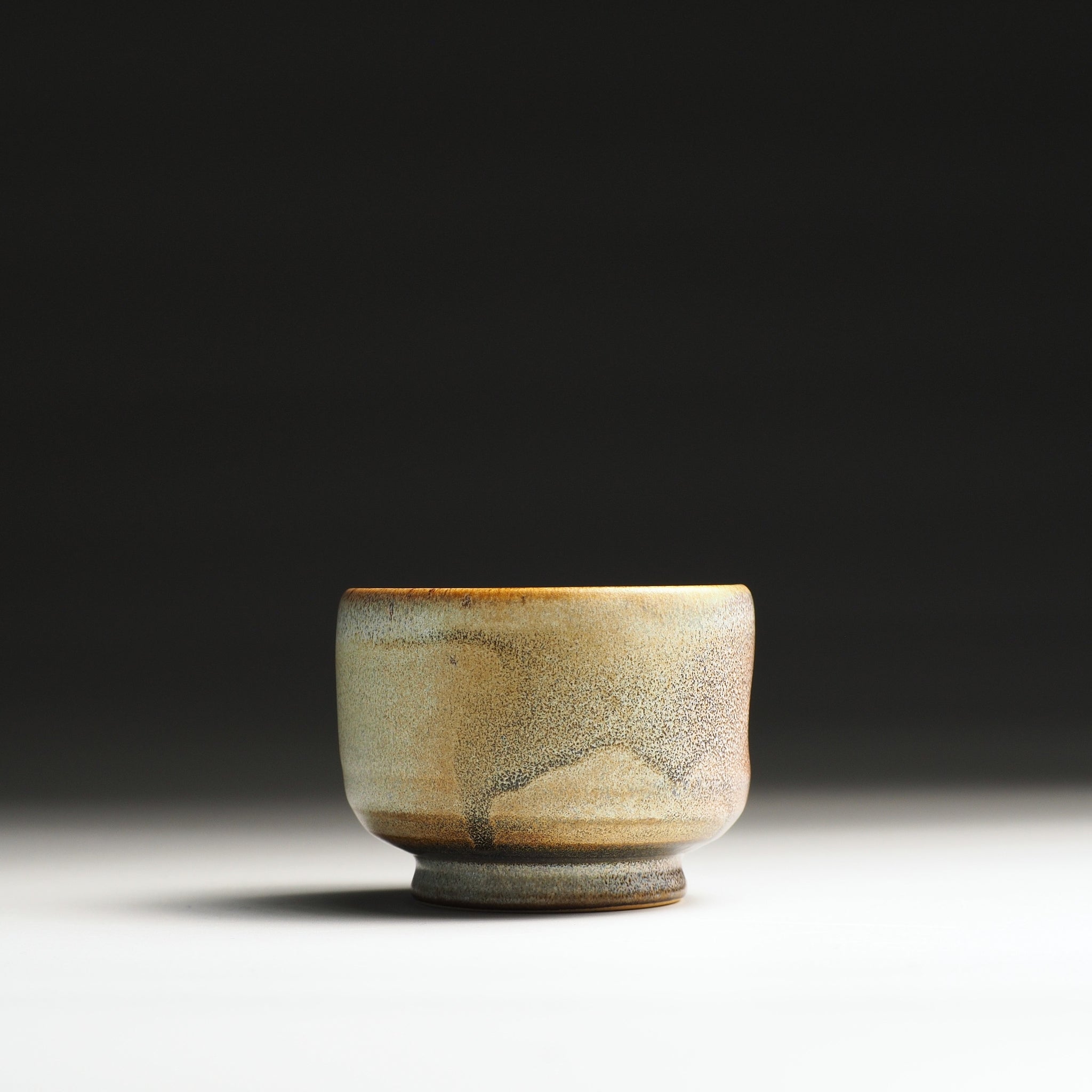 Japanese pottery yunomi with a textured surface on a dark background