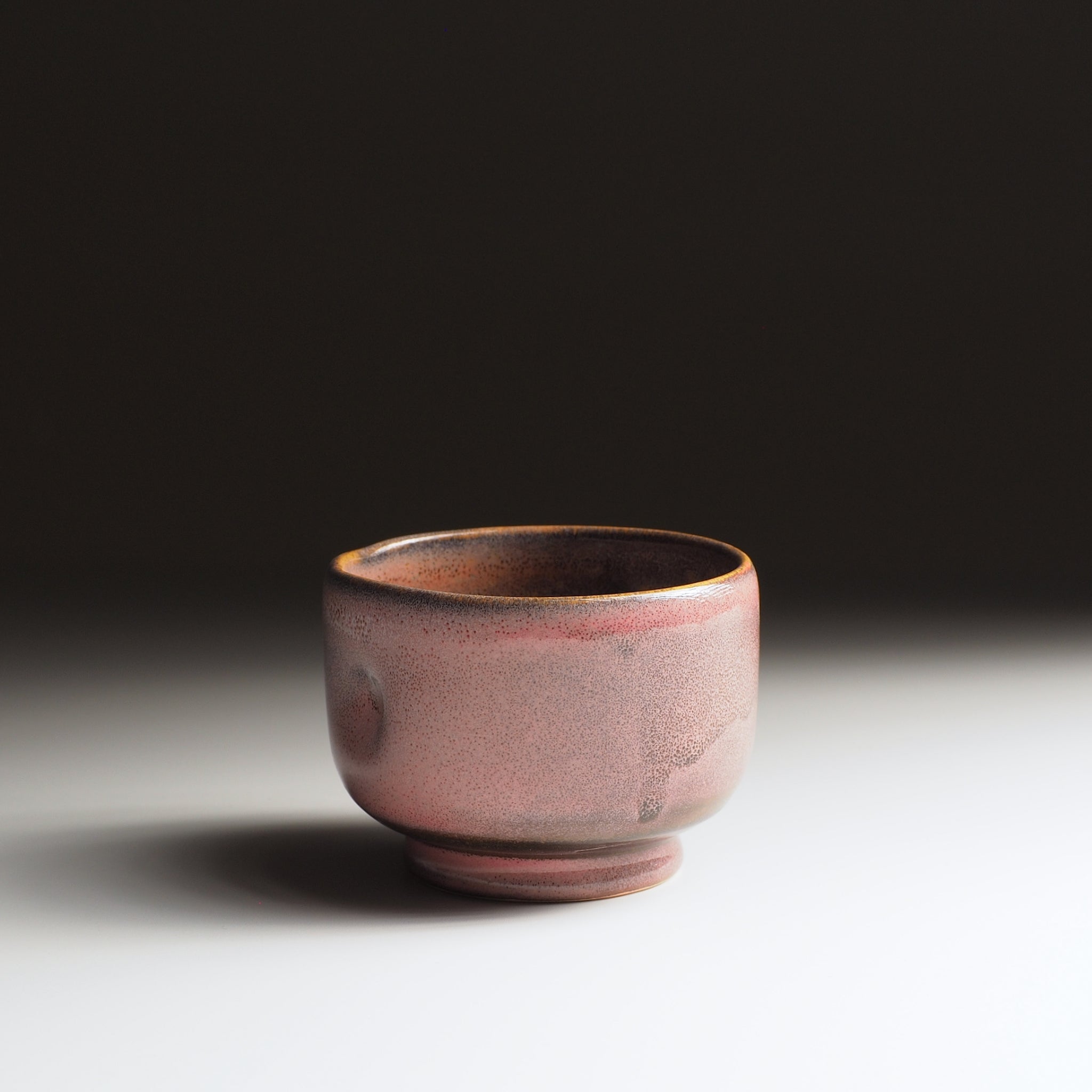 Japanese pink ceramic teacup on a dark background