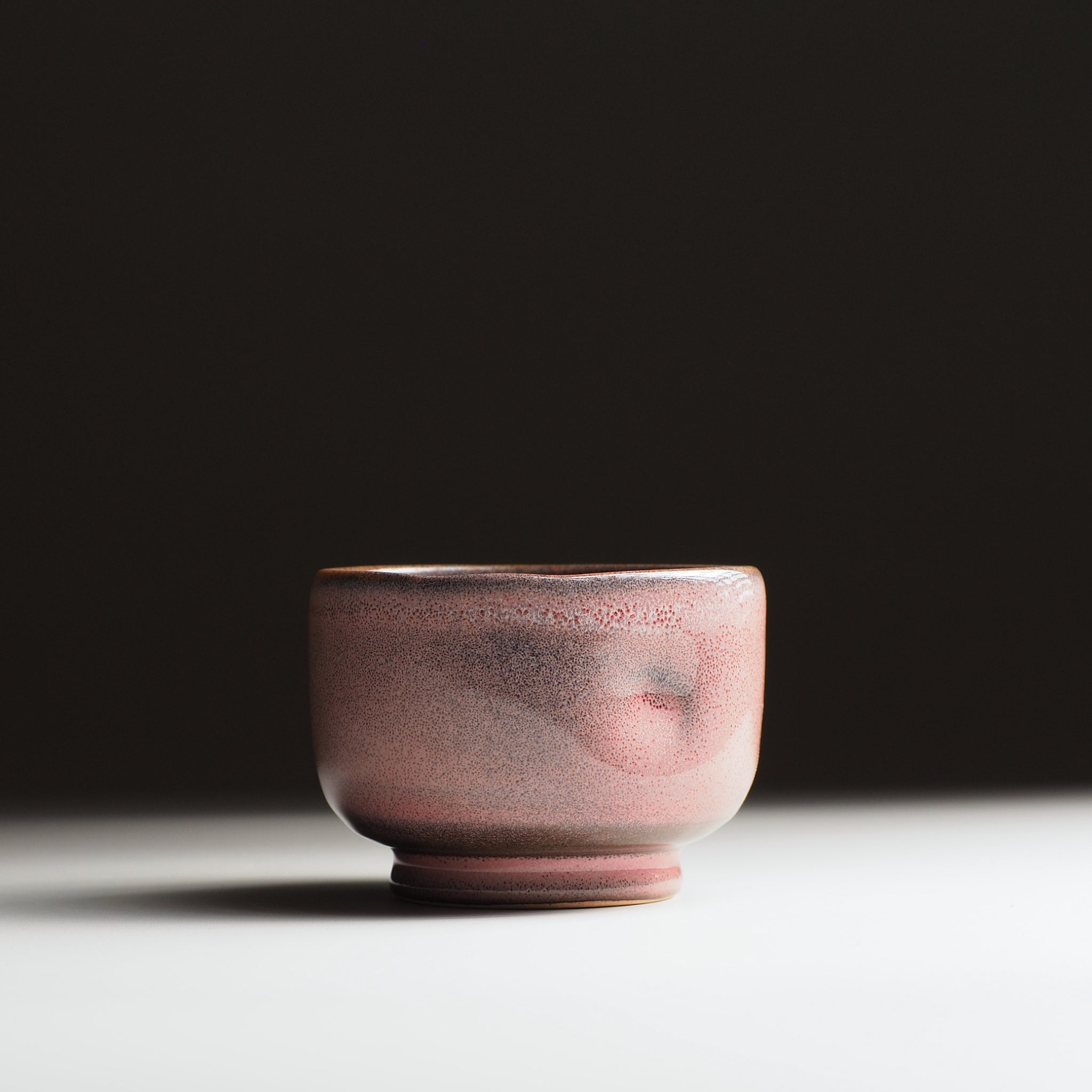 Japanese pink ceramic yunomi cup on a dark background