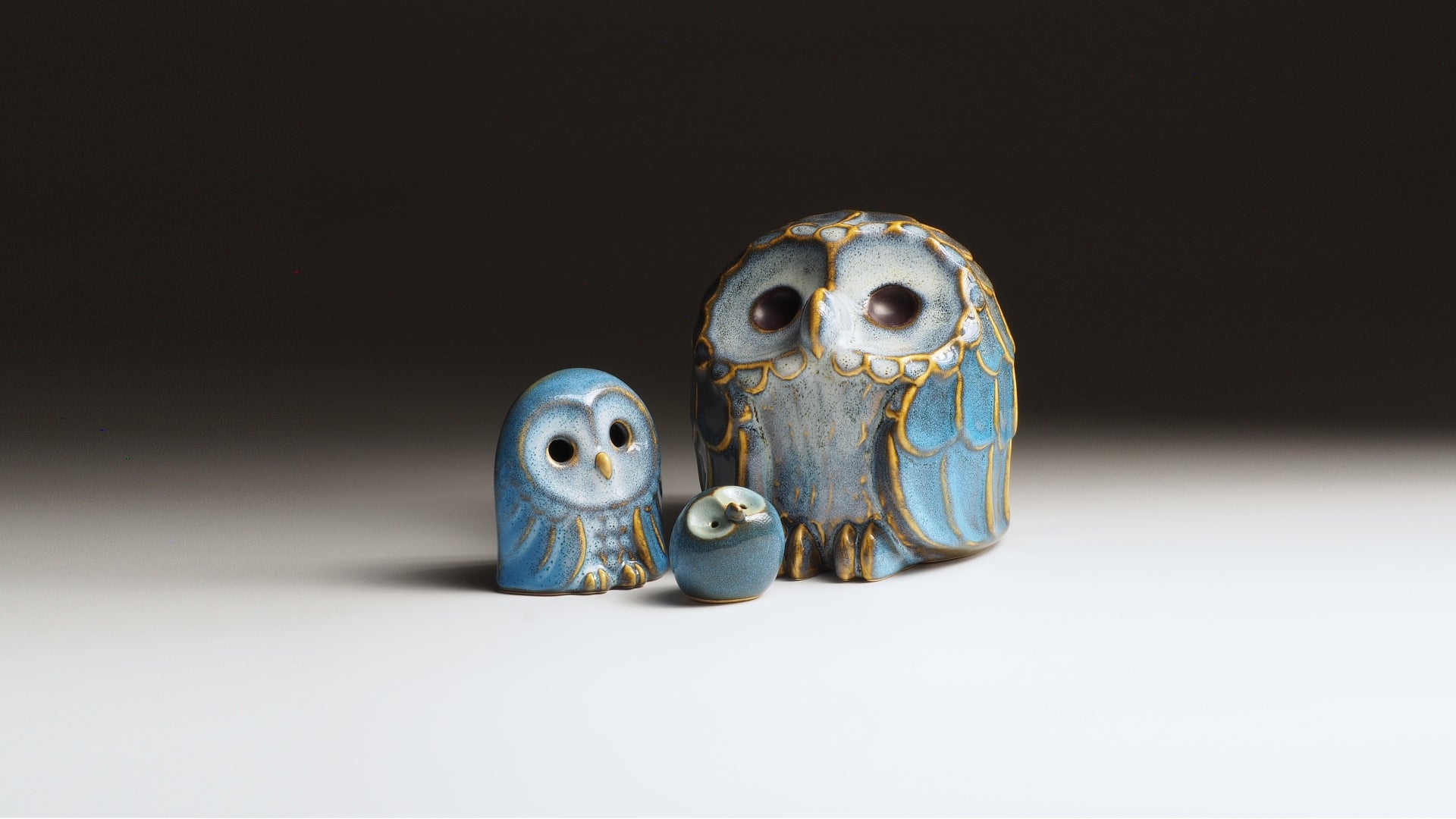 Ceramic owl figurines by Japanese artist Kazuhiro Kojima on a faded background