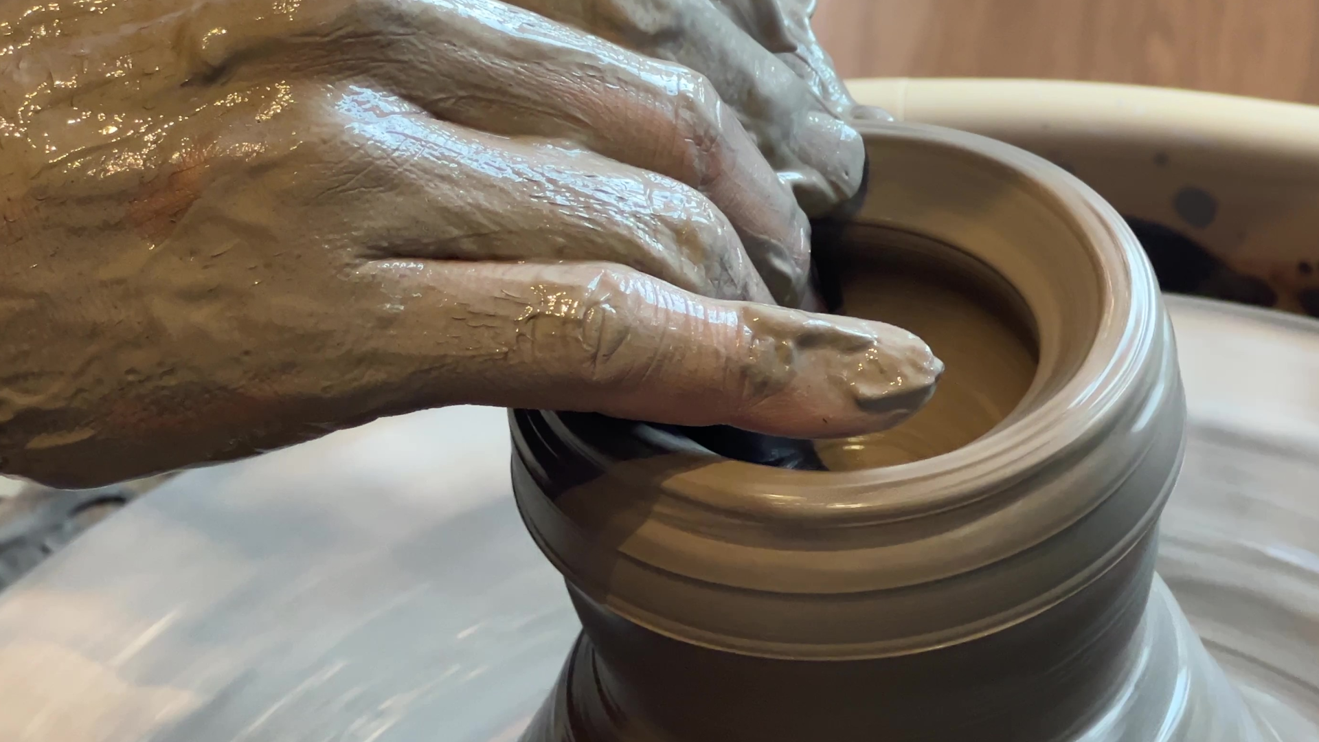 Japanese artisan hands forming a pot on a pottery wheel