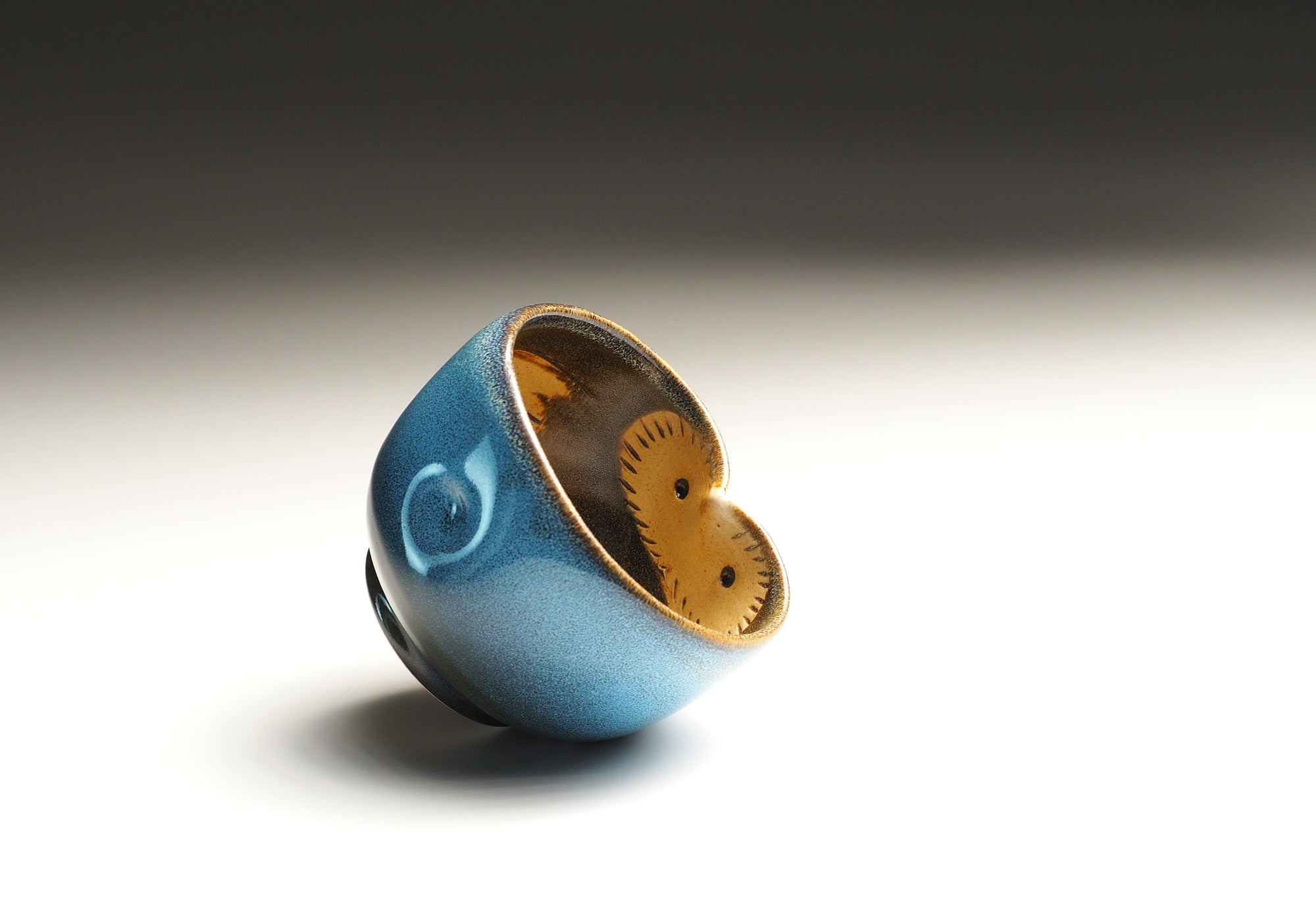 Blue ceramic yunomi teacup with an interior decorated with an owl motif on a gradient background.
