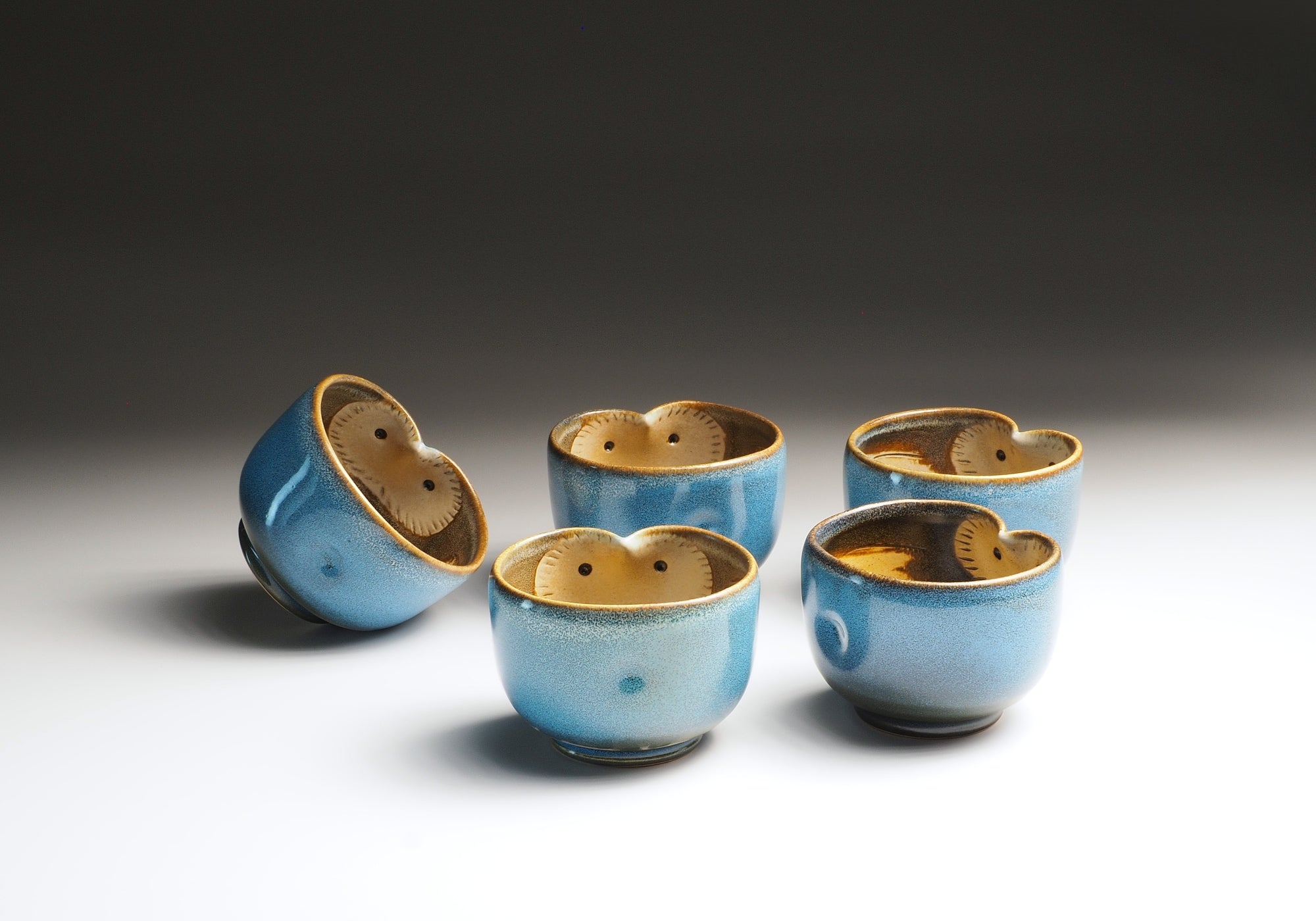 Set of five blue Japanese yunomi with a owl design on a gradient background