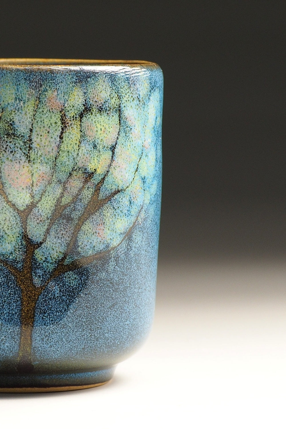 Detail of a Japanese yunomi cup with tree design on a gradient background
