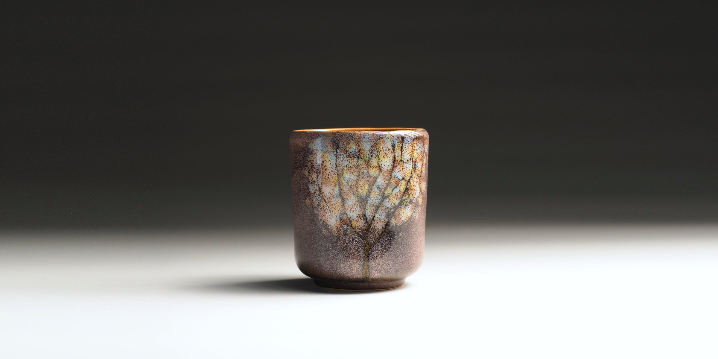 Front view of pink Japanese teacup with tree motifs.