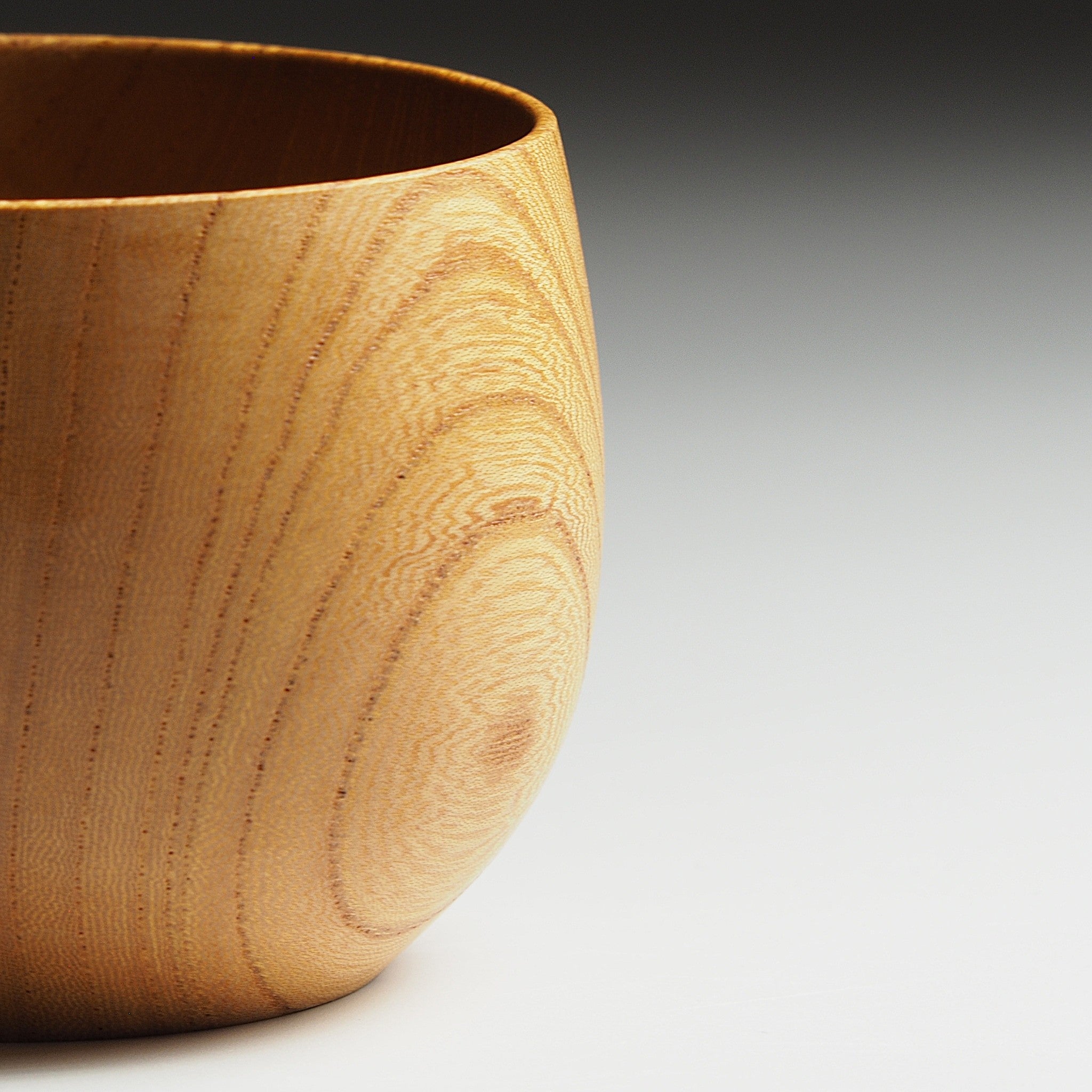 A close-up of a Japanese wooden cup on a gradient background. Tsukushi