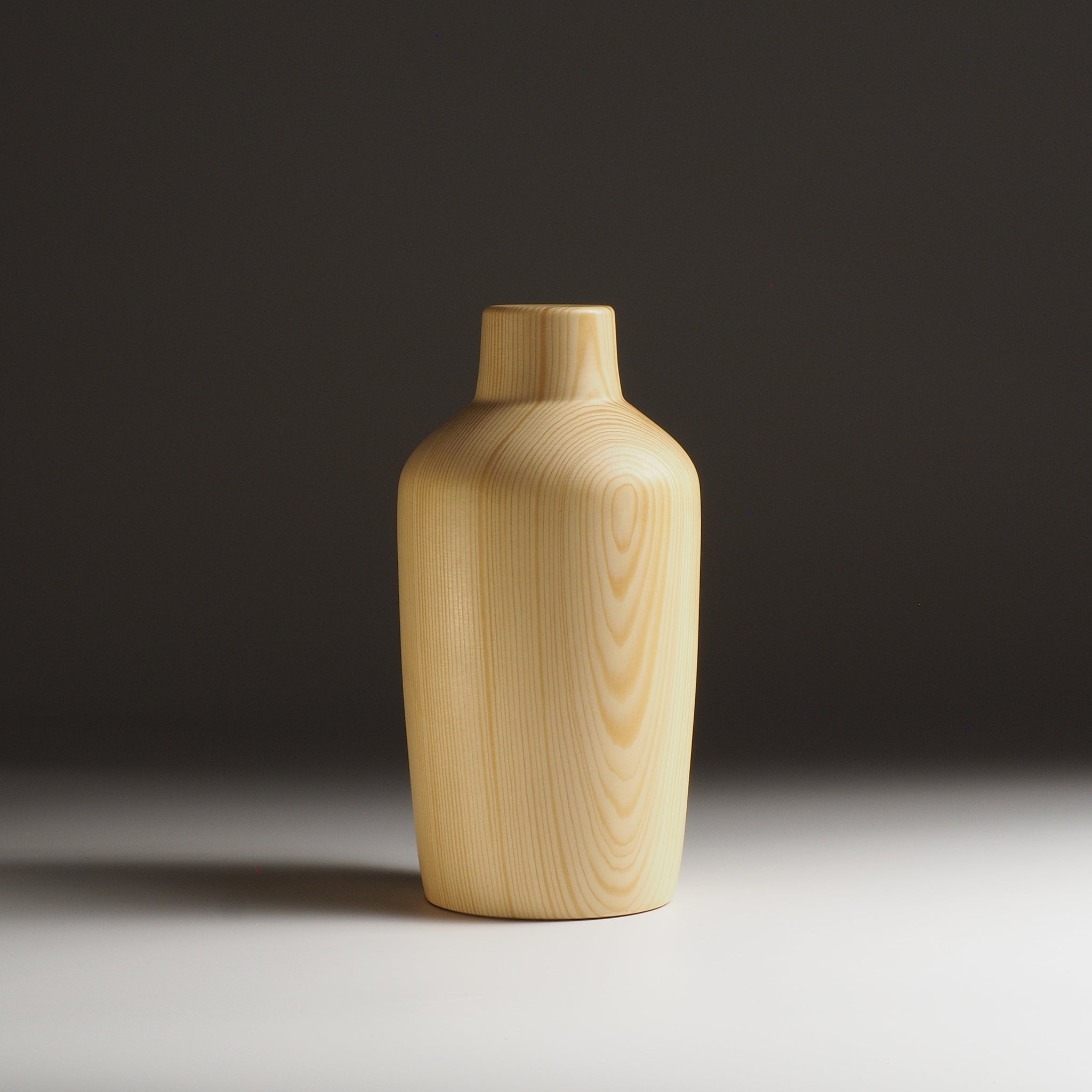 A Japanese wooden vase on a beige gradient background. Tsukushi