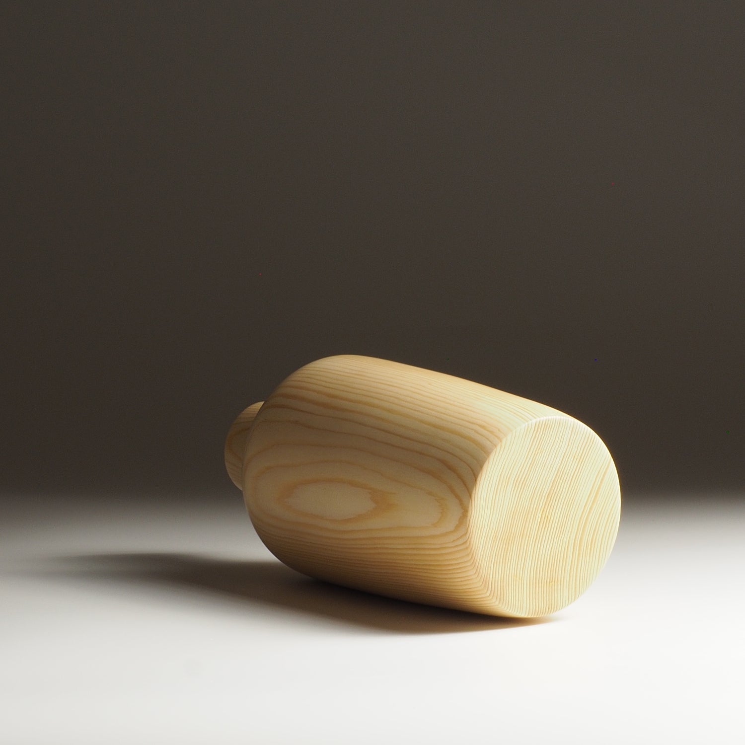 A Japanese wooden vase on a dark beige background. Tsukushi
