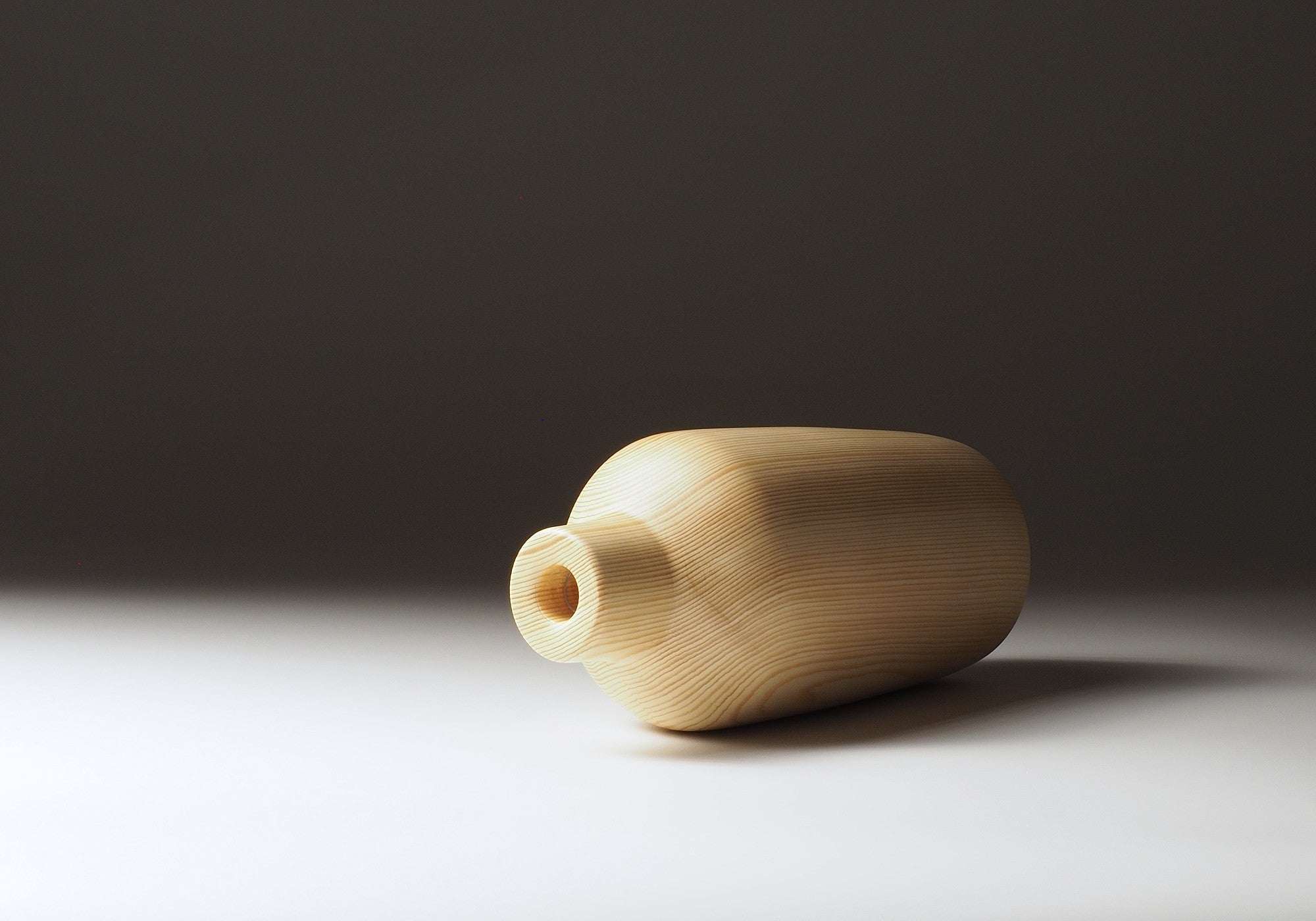 A Japanese wooden vase called Shinon on a dark beige background. Tsukushi