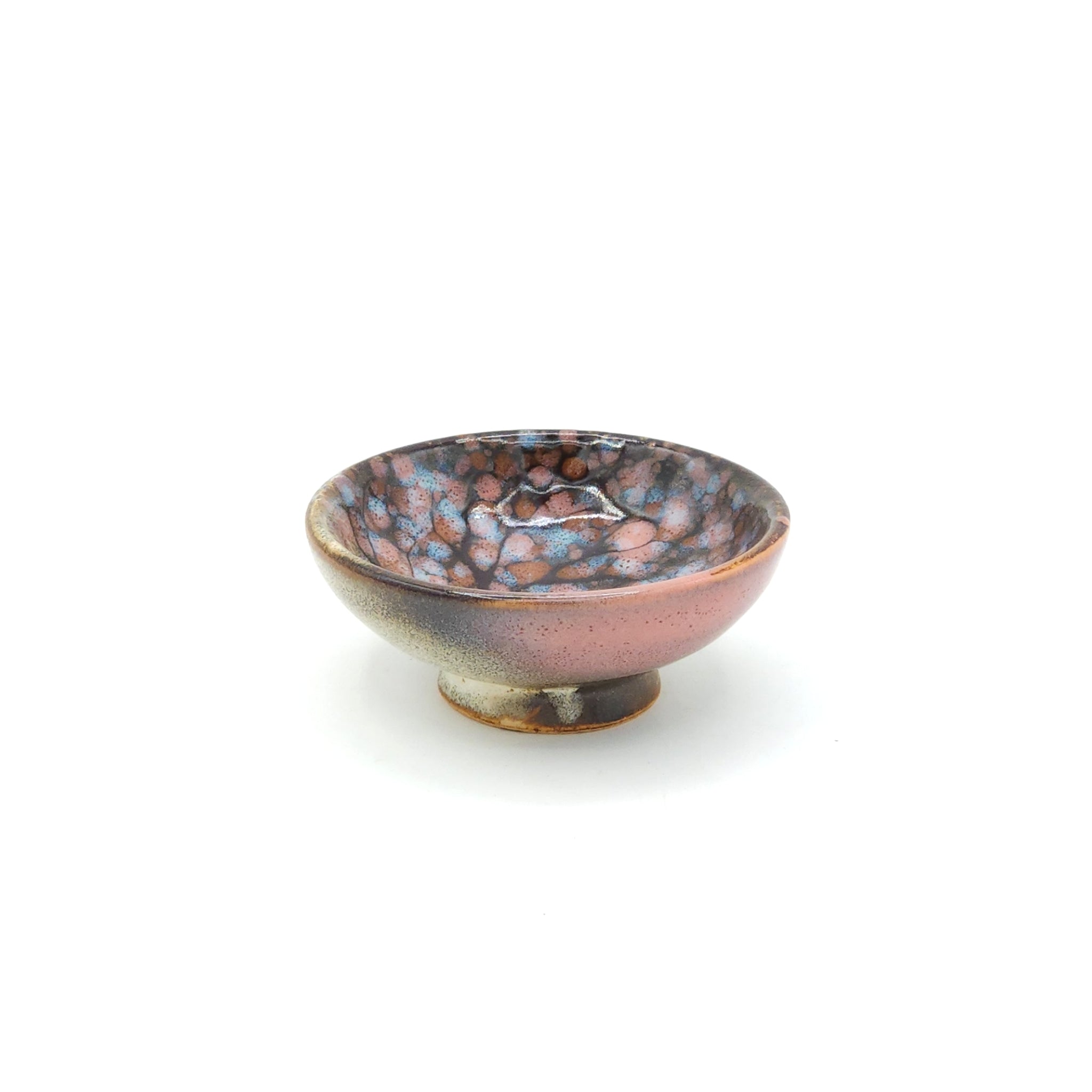A side view of  a flat Japanese ceramic sake cup with a cherry blossom motif. Tsukushi