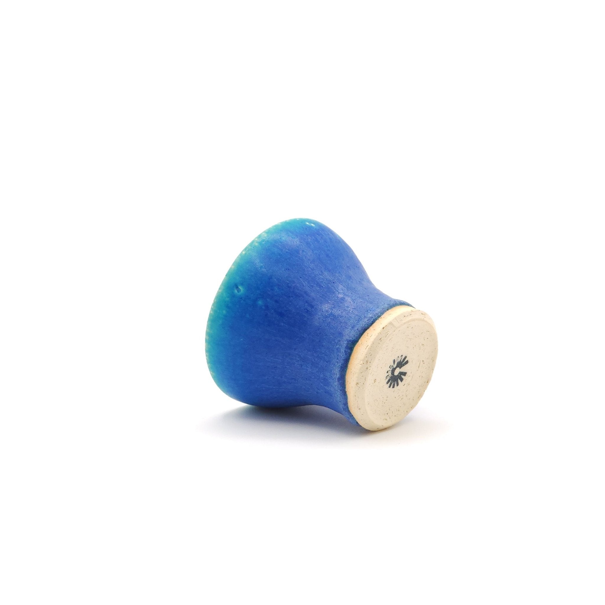 View from back of a turquoise Japanese pottery small cup on one side.