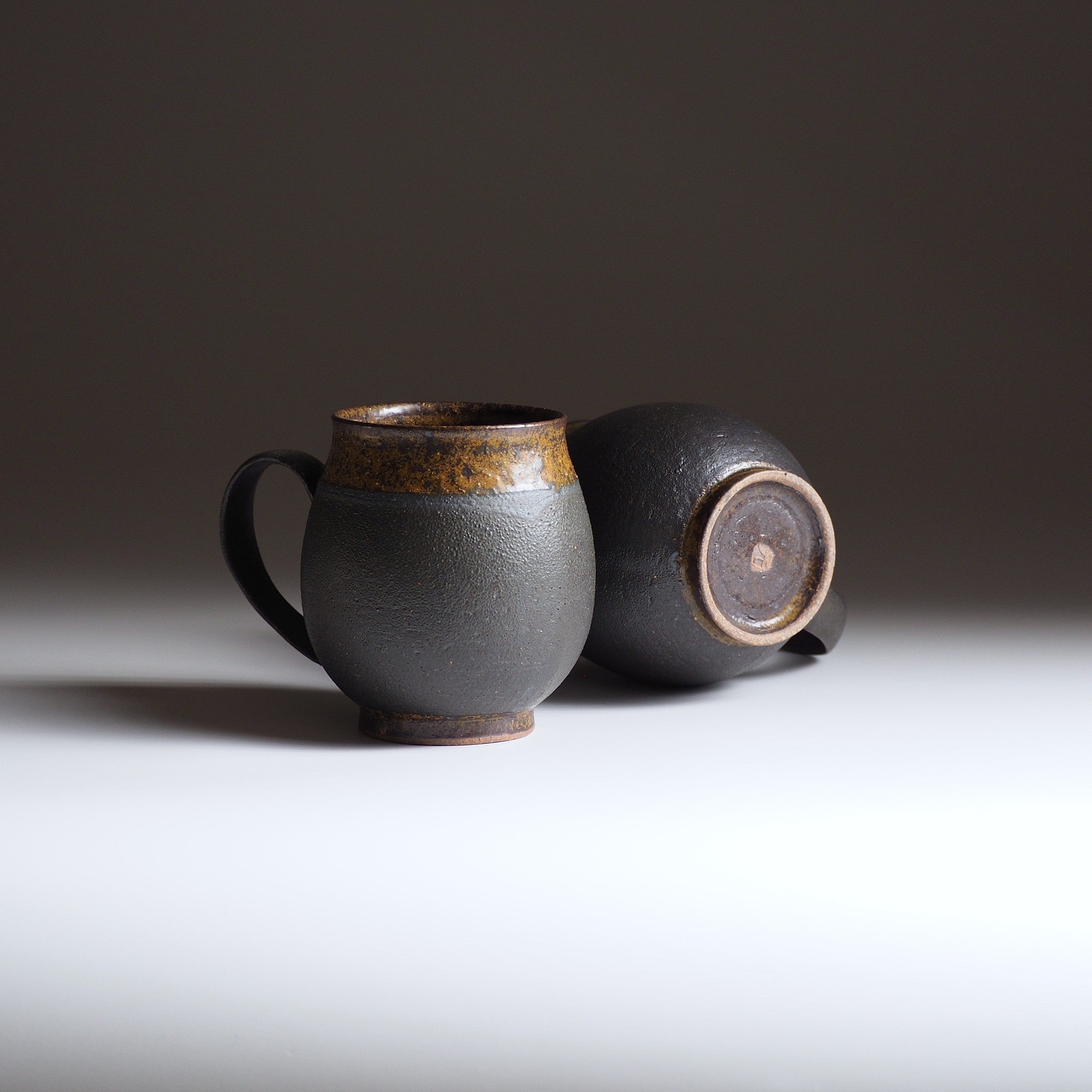 Two Japanese ceramic mugs on a white surface with a dark background
