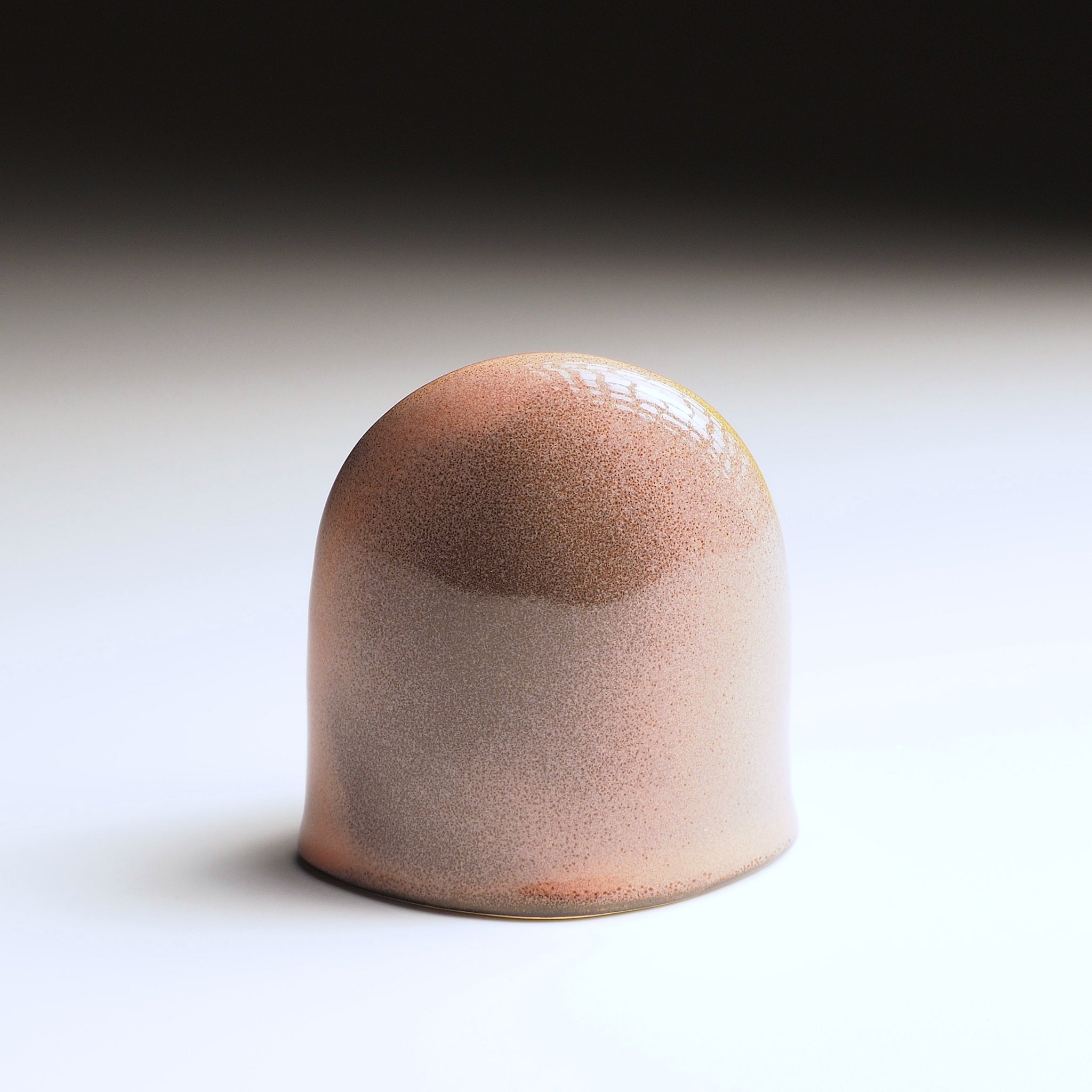 Engifuku owl figurine by Kazuhiro Kojima seen from the back, pink and grey speckled glaze, golden details, hollow eyes.