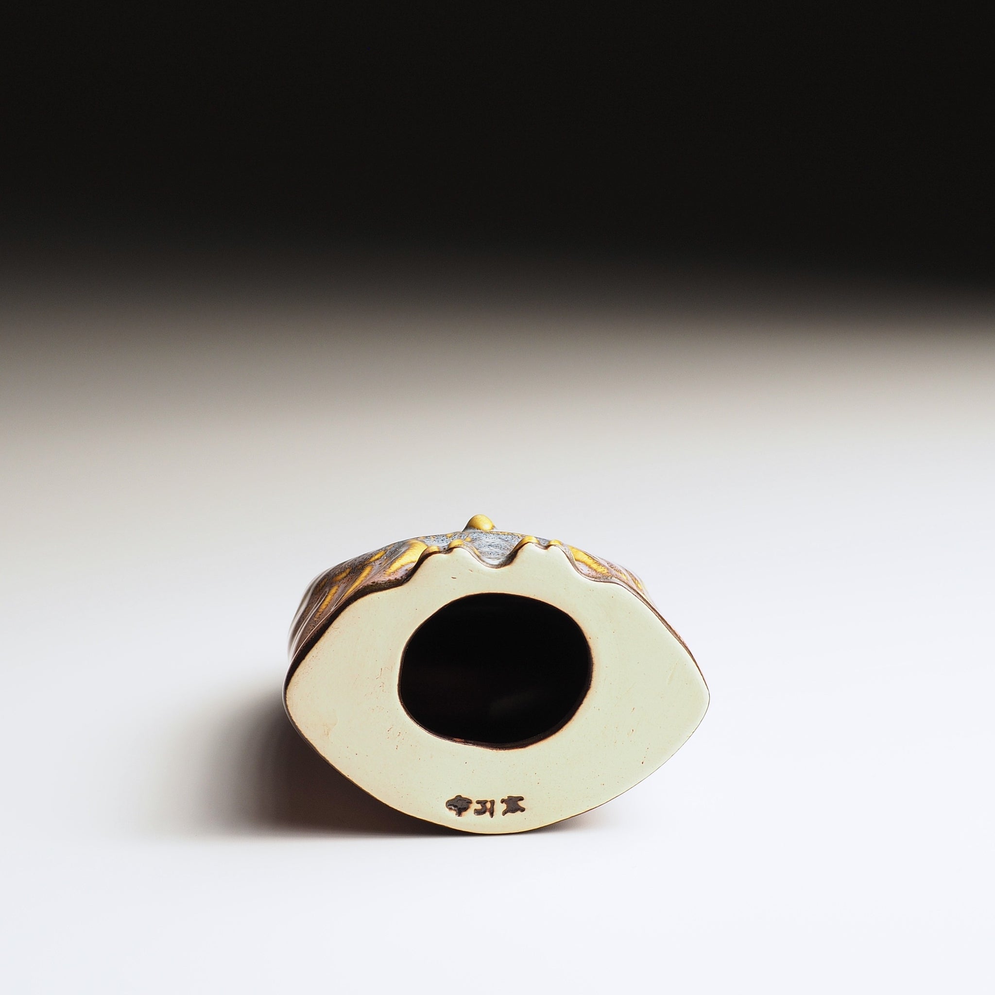 Bottom view of the Pink Engifuku owl figurine by Kazuhiro Kojima on a gradient background.