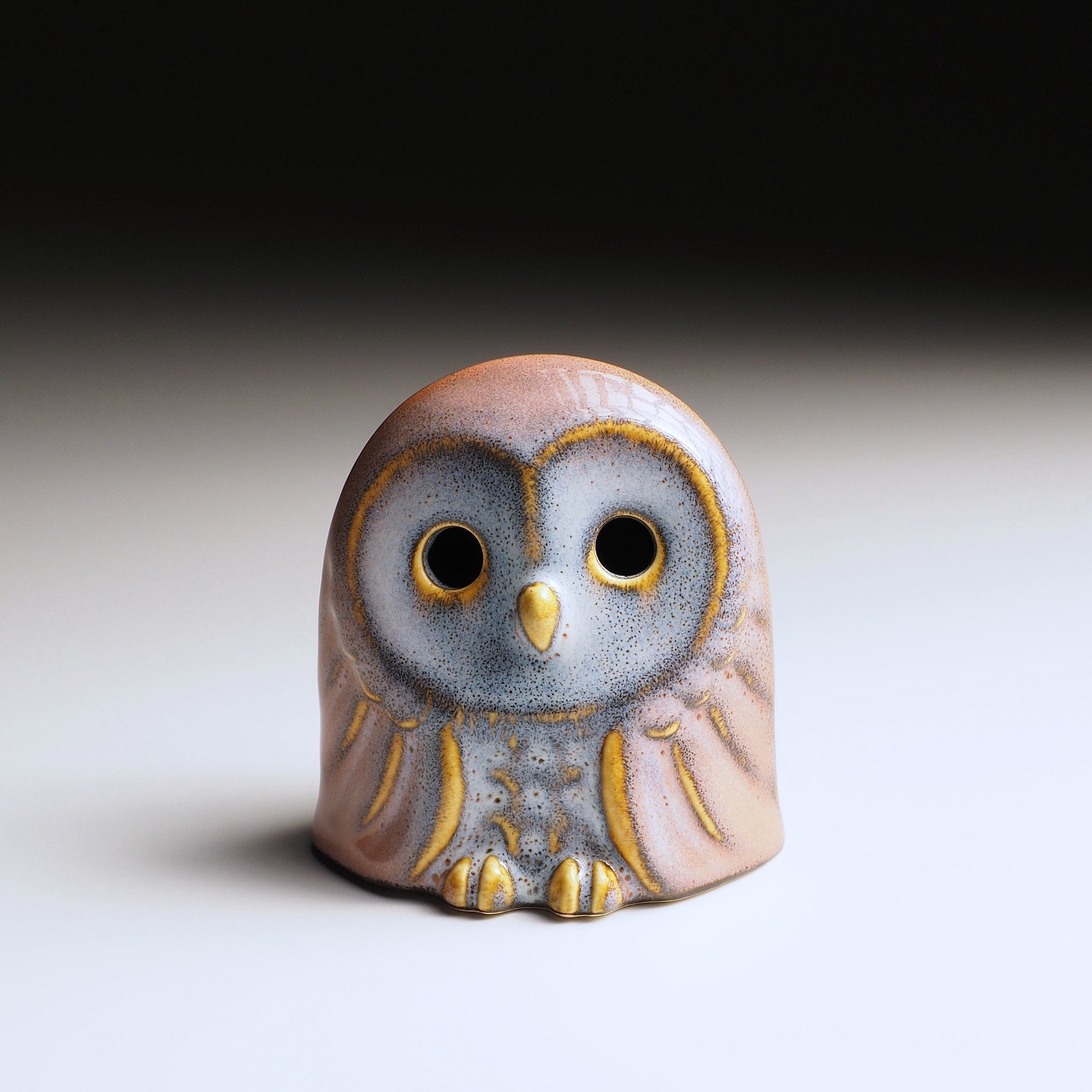 Engifuku owl figurine by Kazuhiro Kojima seen from the front, pink and grey speckled glaze, golden details, hollow eyes.