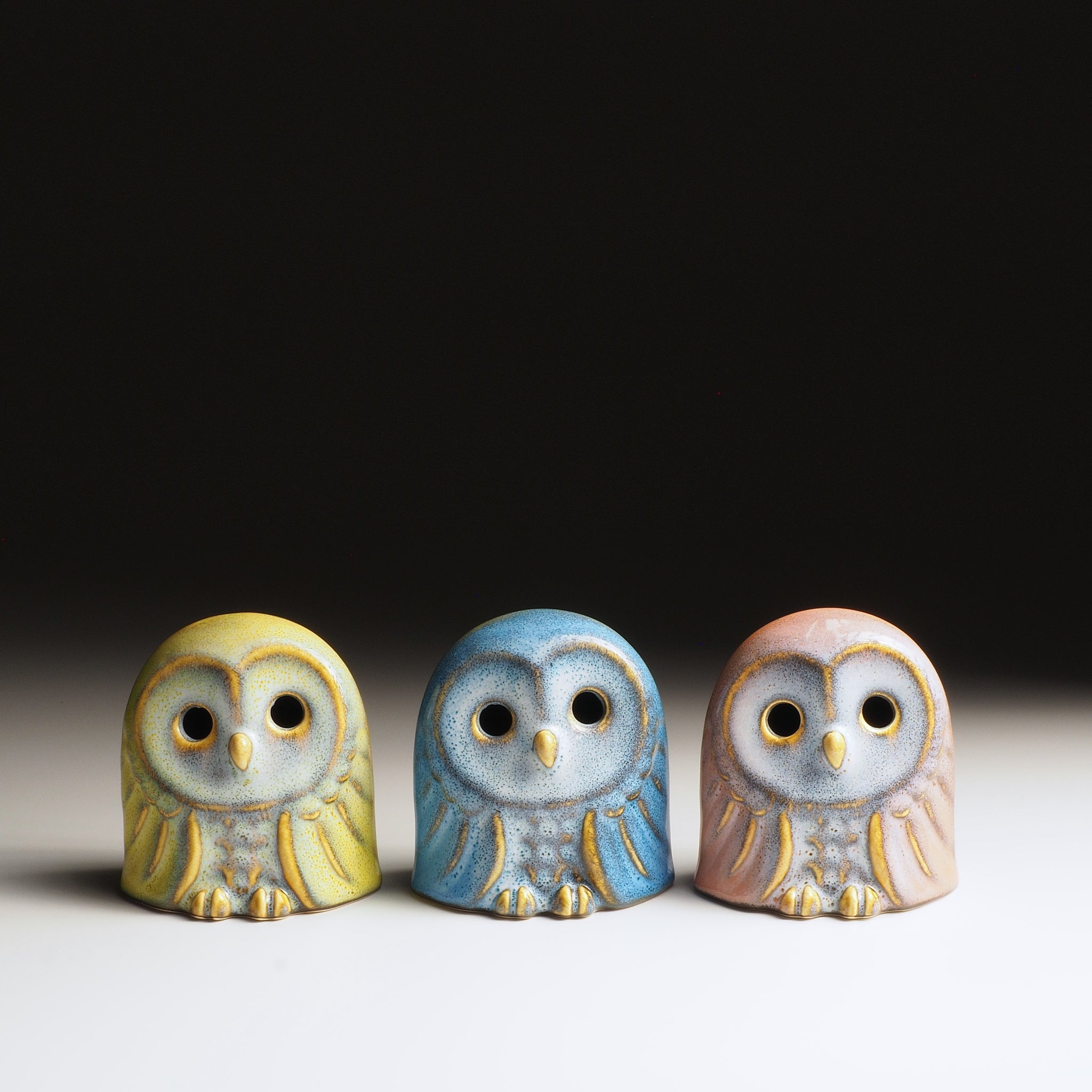 Three ceramic owl figurines of the Engifuku set in different colors on a neutral background