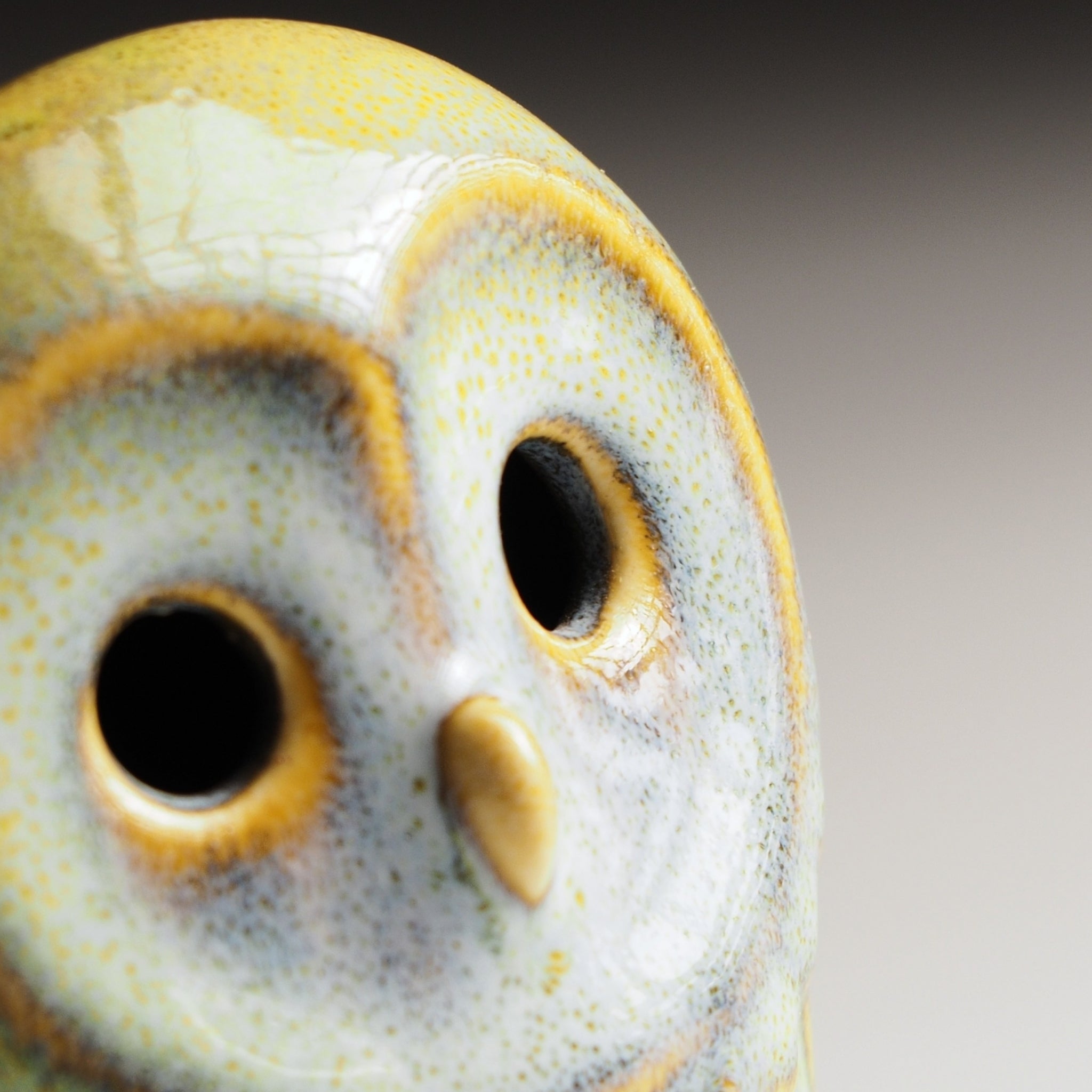 Close-up  view of Engifuku owl figurine by Kazuhiro Kojima, blue speckled ceramic glaze, golden accents, hollow eyes, gradient background.