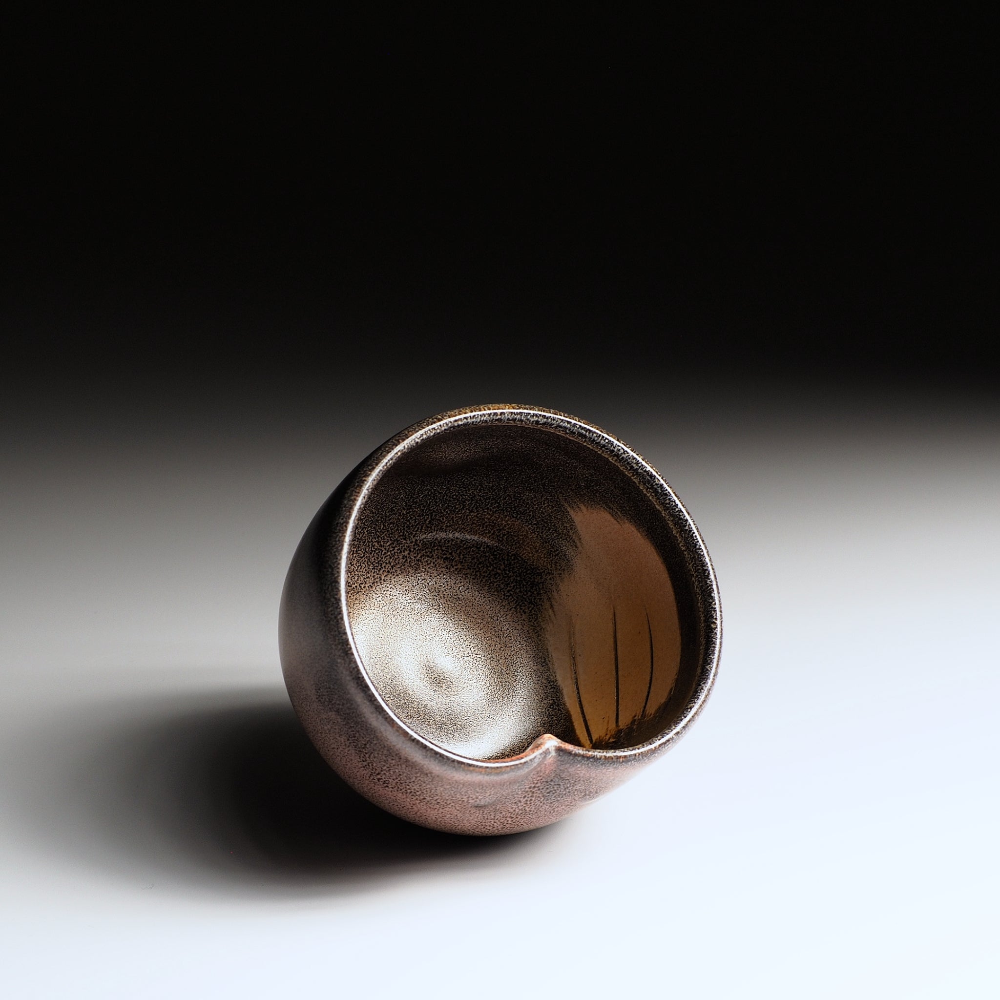 Interior view of a Japanese ceramic teacup with a owl wing motif on a gradient background