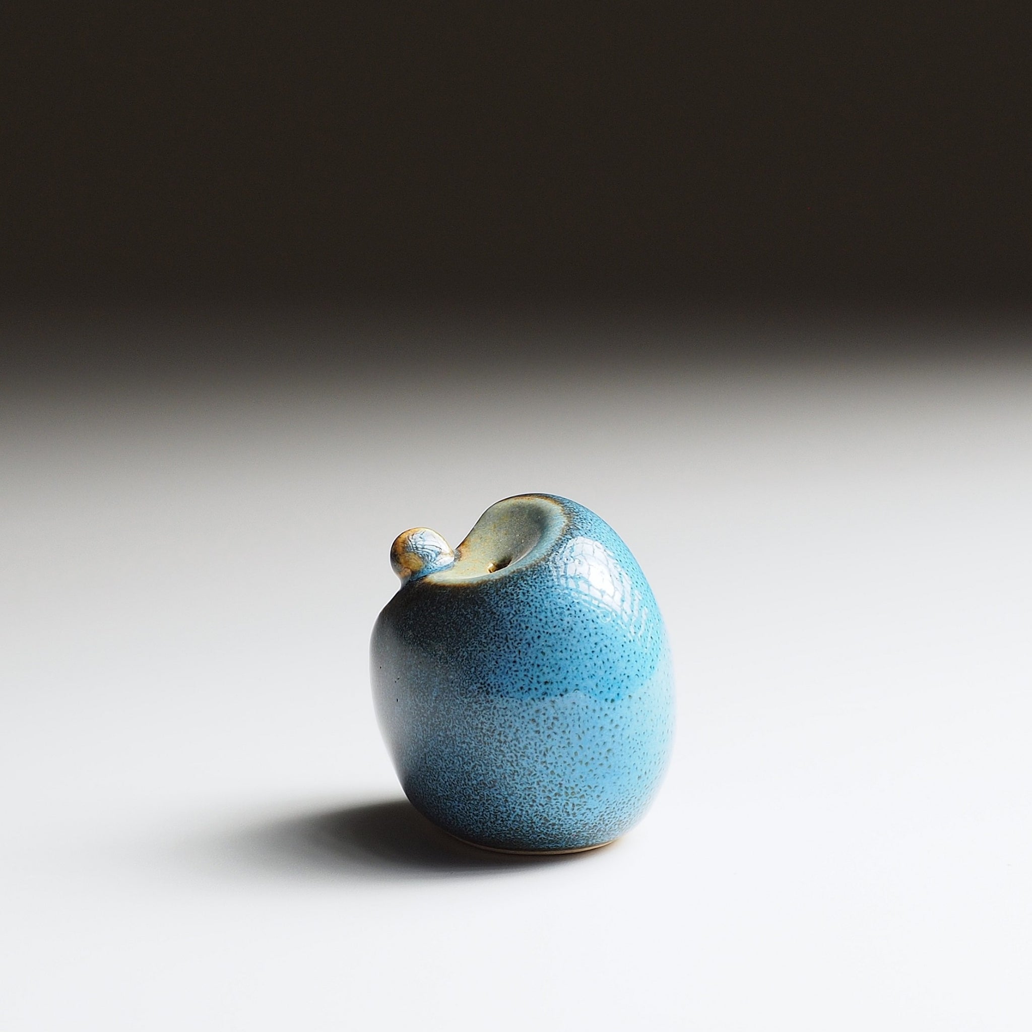 Twilight blue Gofuku ceramic owl figurine, left profile showing curved body contour and sculptural gold beak detail.