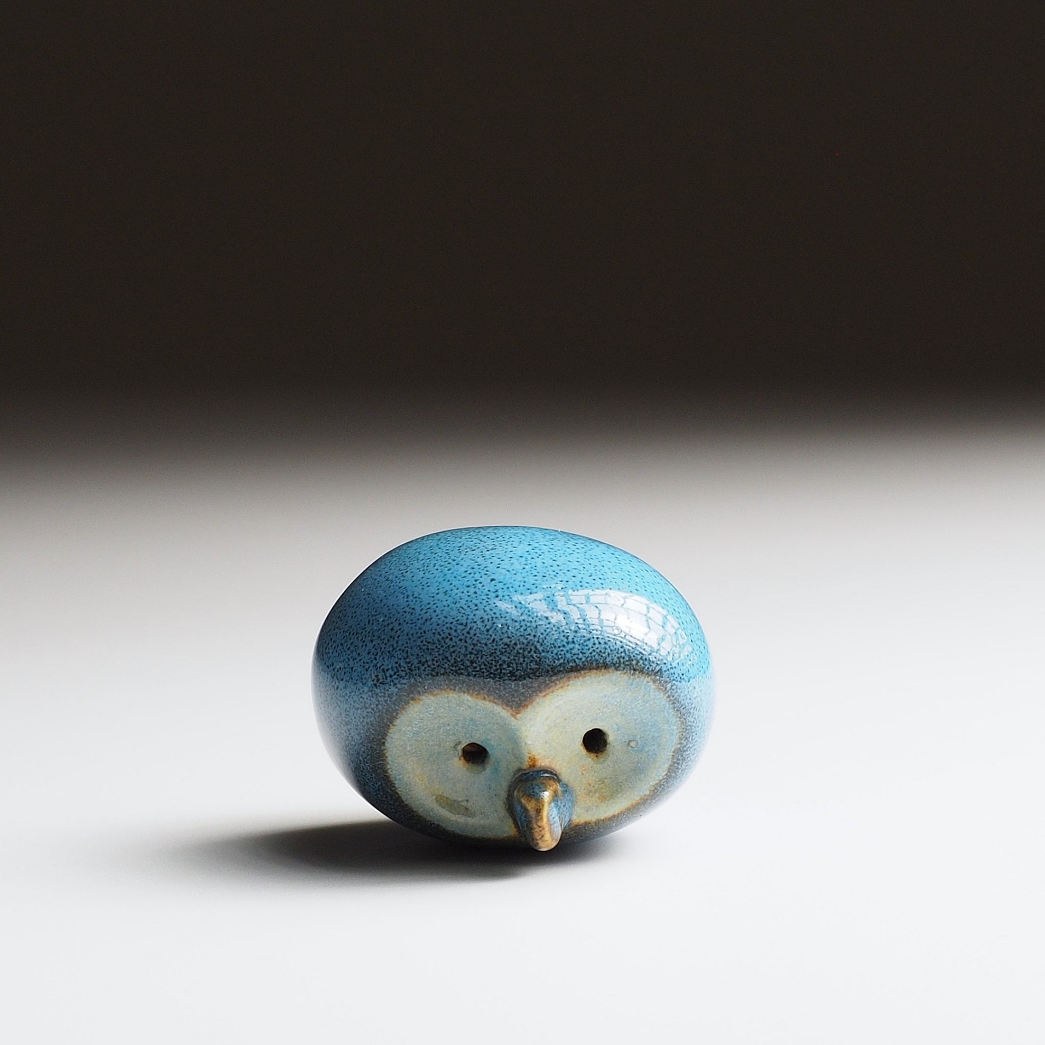 Twilight blue Gofuku ceramic owl figurine, top view showing rounded form, gold beak, and detailed eye markings.