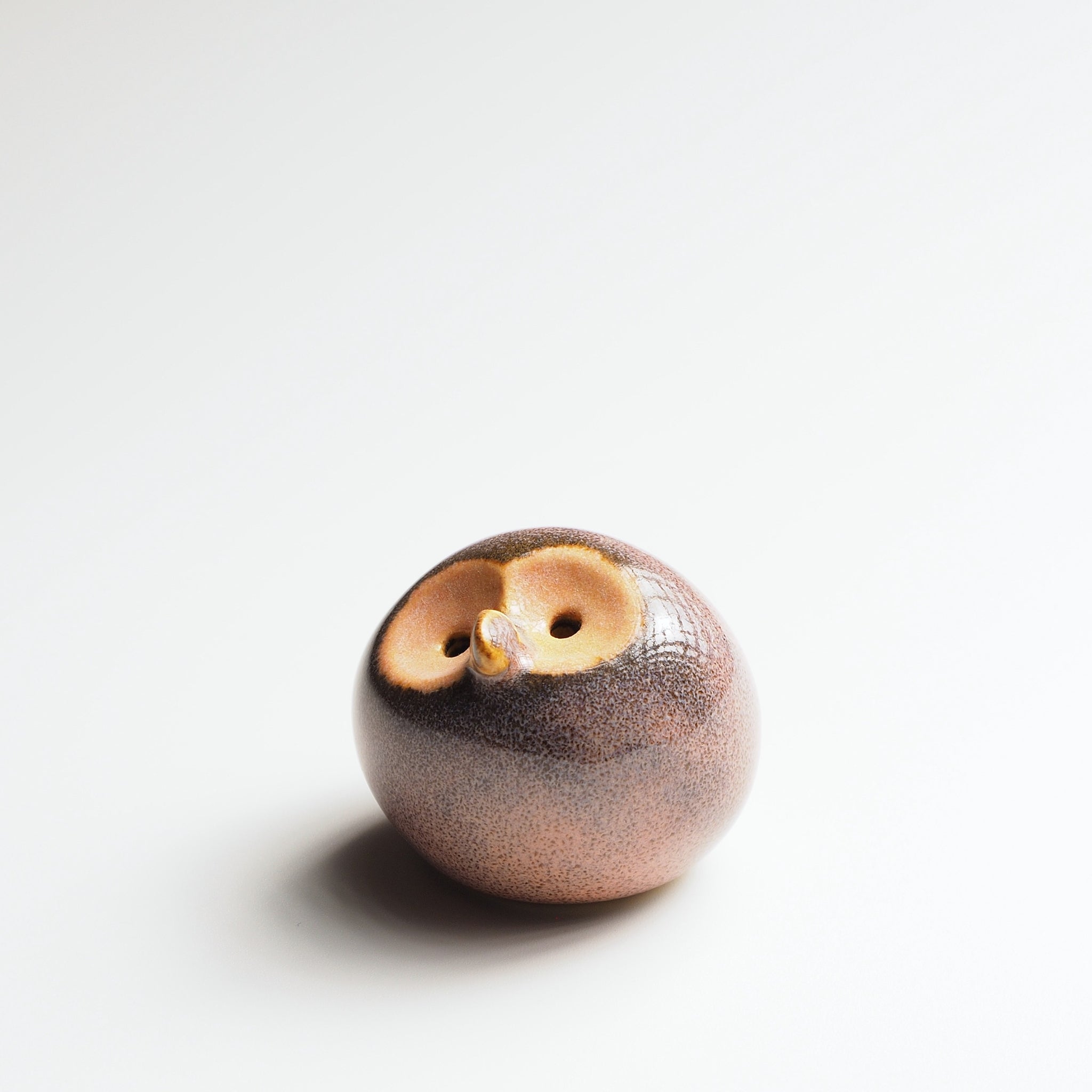 Dusk plum Gofuku ceramic owl figurine with gold-glazed face and eyes, close detail of handcrafted glaze and surface texture.