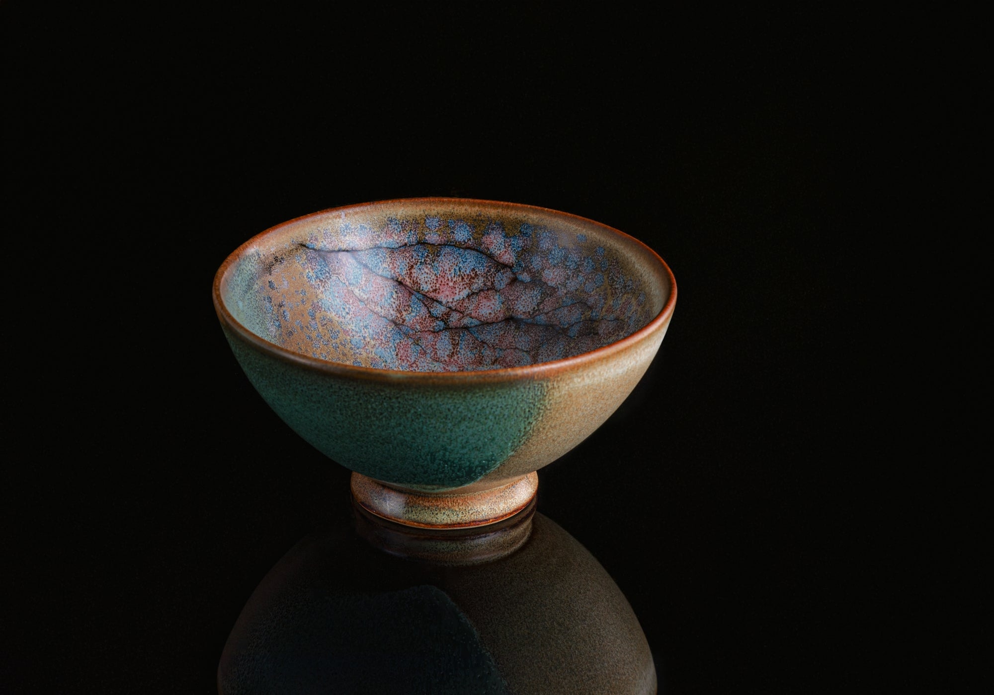 A Japanese ceramic bowl with cherry blossoms pattern on a dark background. Tsukushi