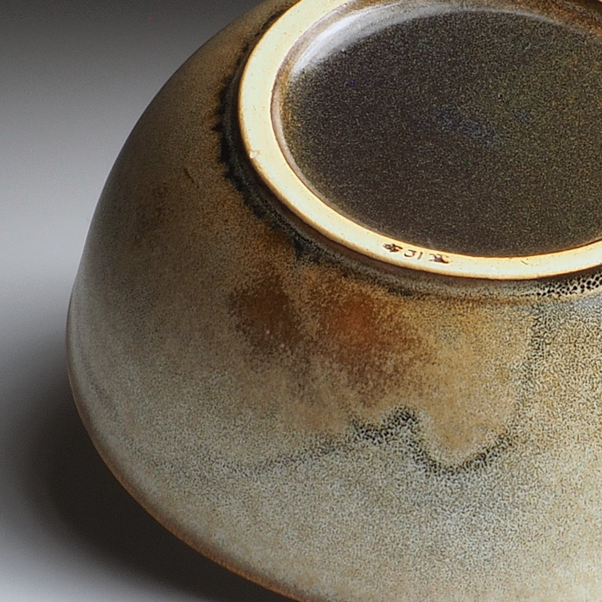 Close-up of a ceramic bowl foot with a textured surface on a gray background