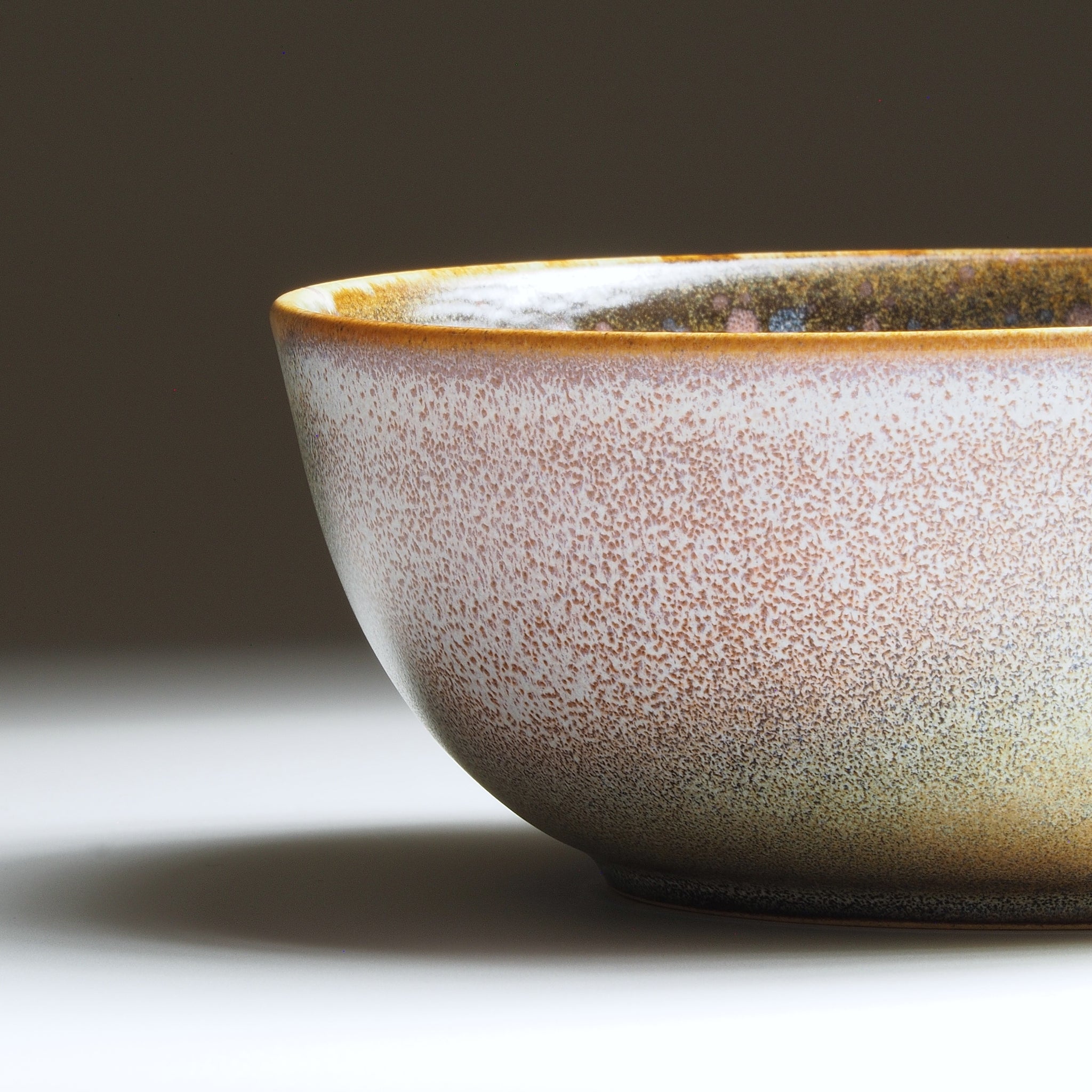 Side view of the Harukaze Pink Cherry Blossoms salad bowl by Kazuhiro Kojima on a faded background.