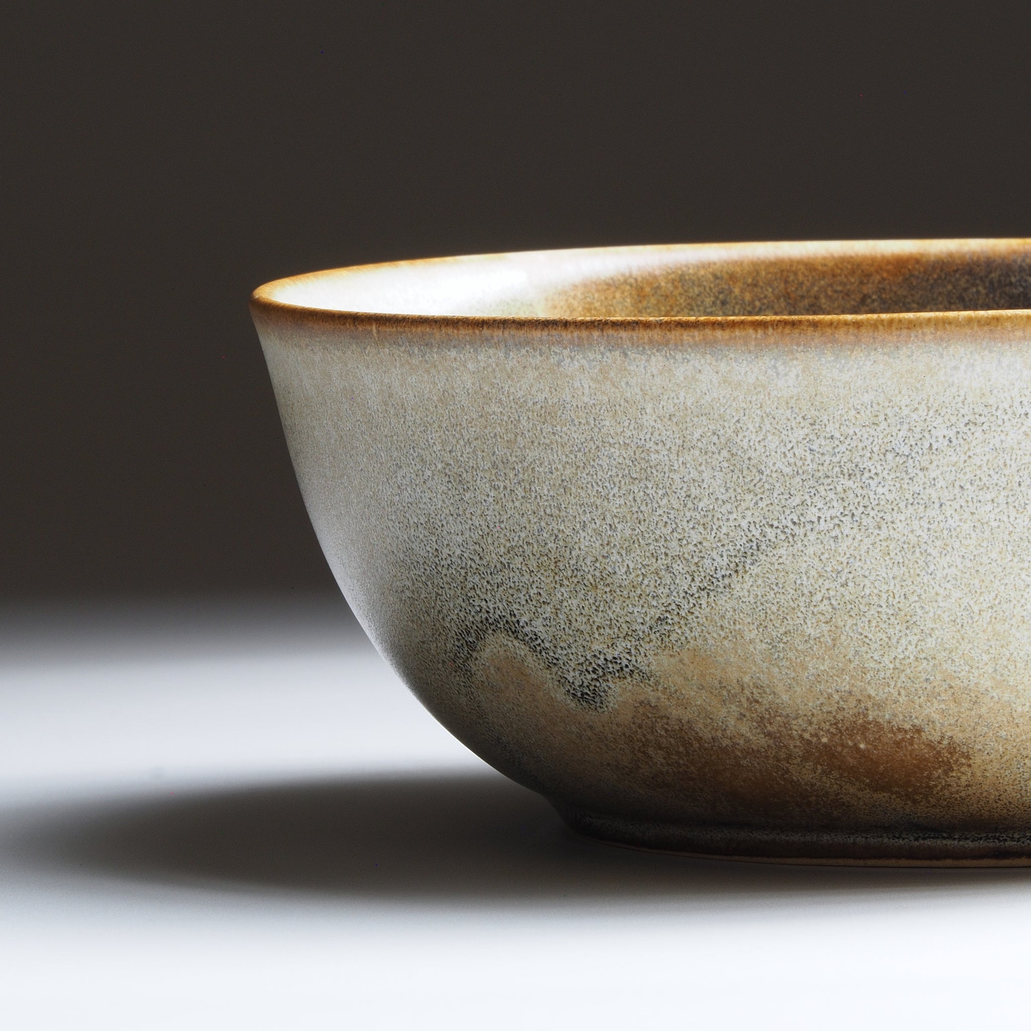 Rim close-up view of the Harukaze Pink Cherry Blossoms salad bowl by Kazuhiro Kojima on a faded background.