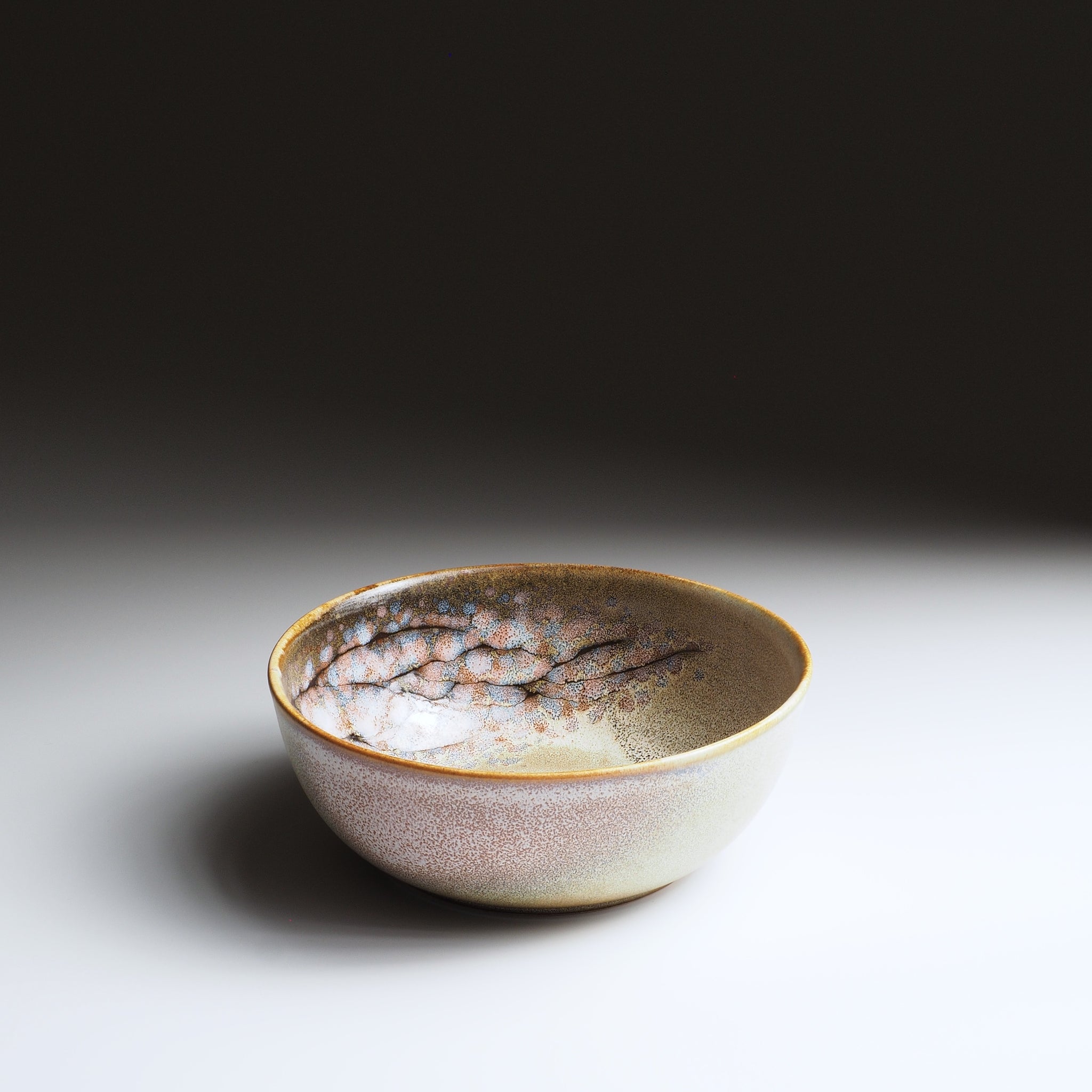 3/4 view of the Harukaze Cherry Blossoms pink salad bowl by Kazuhiro Kojima on a faded background.