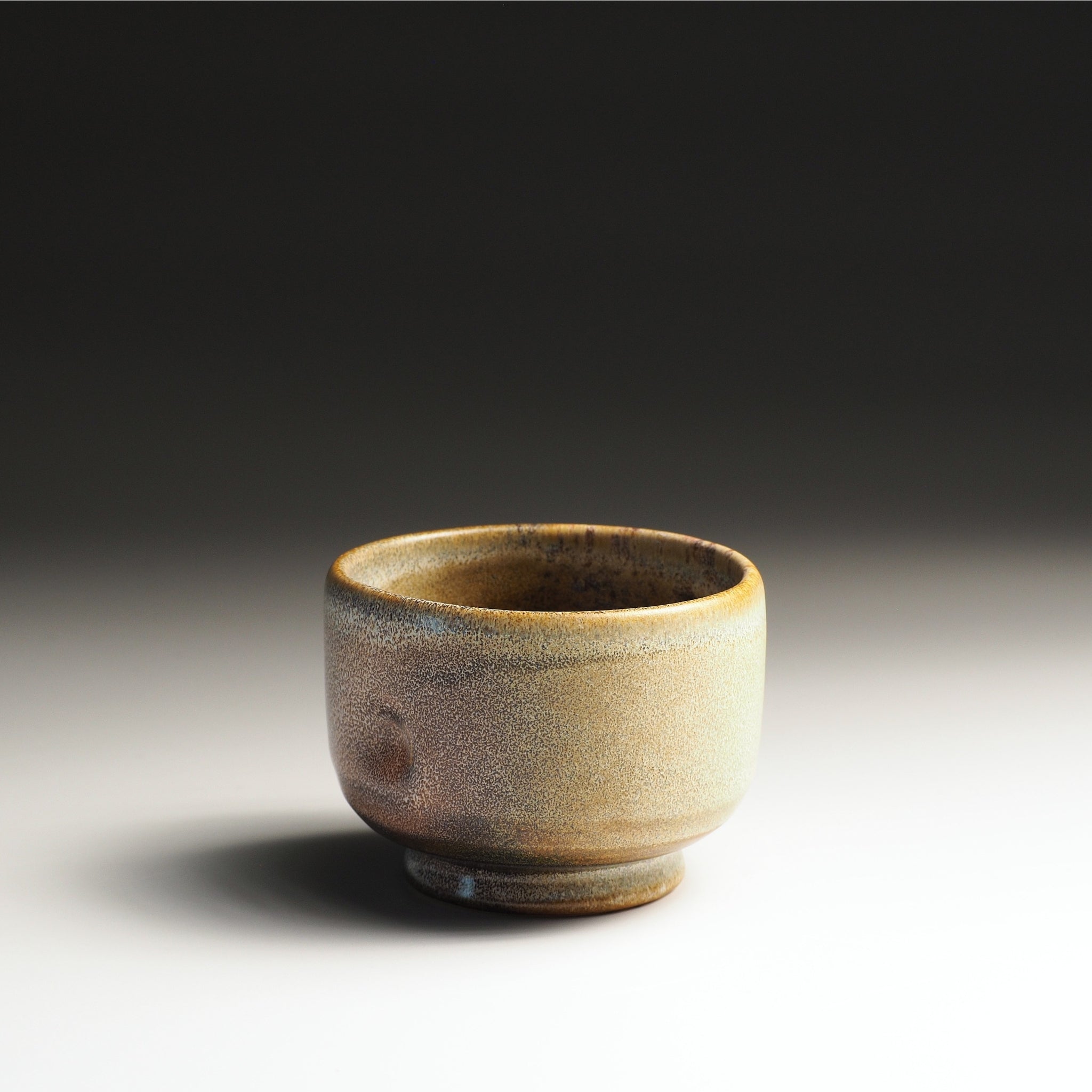 Japanese pottery yunomi with a textured surface on a studio gradient background