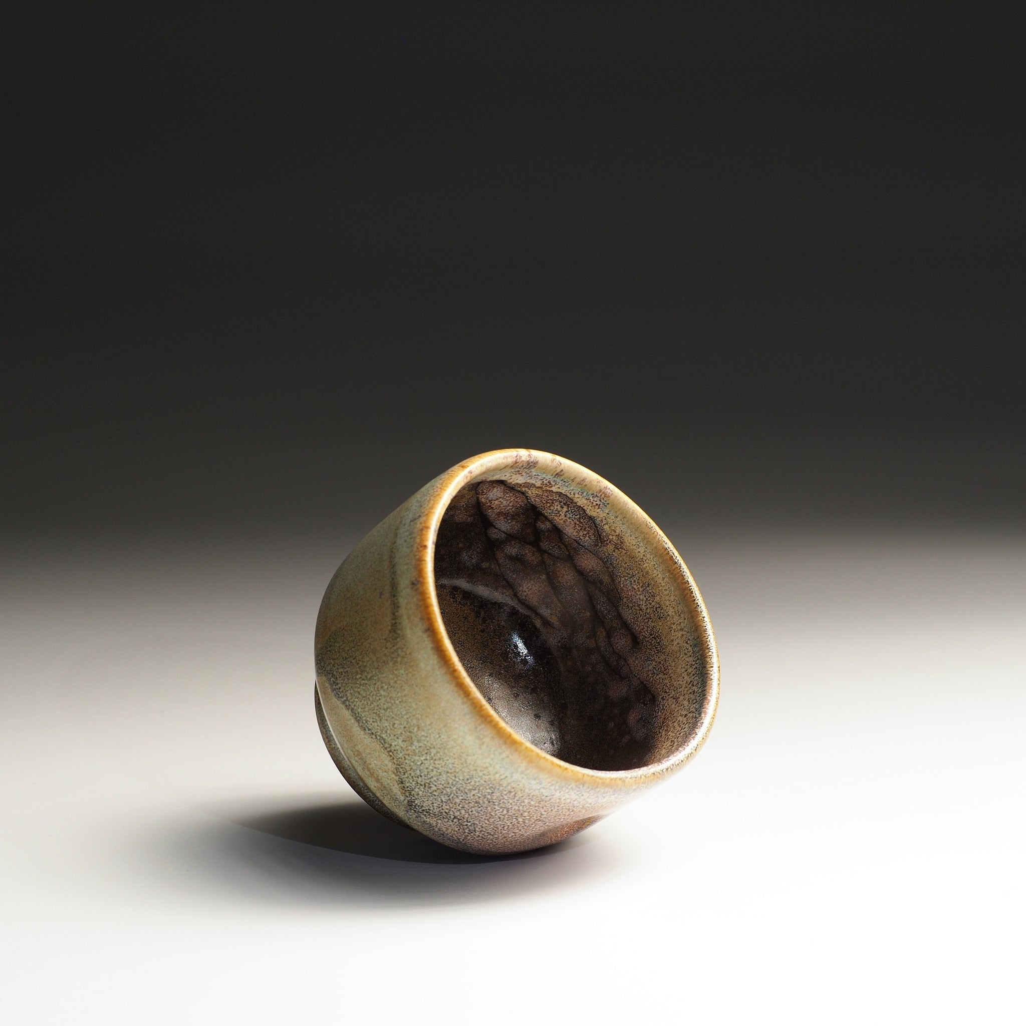 Side view of a pottery yunomi teacup with a textured surface on a gradient background