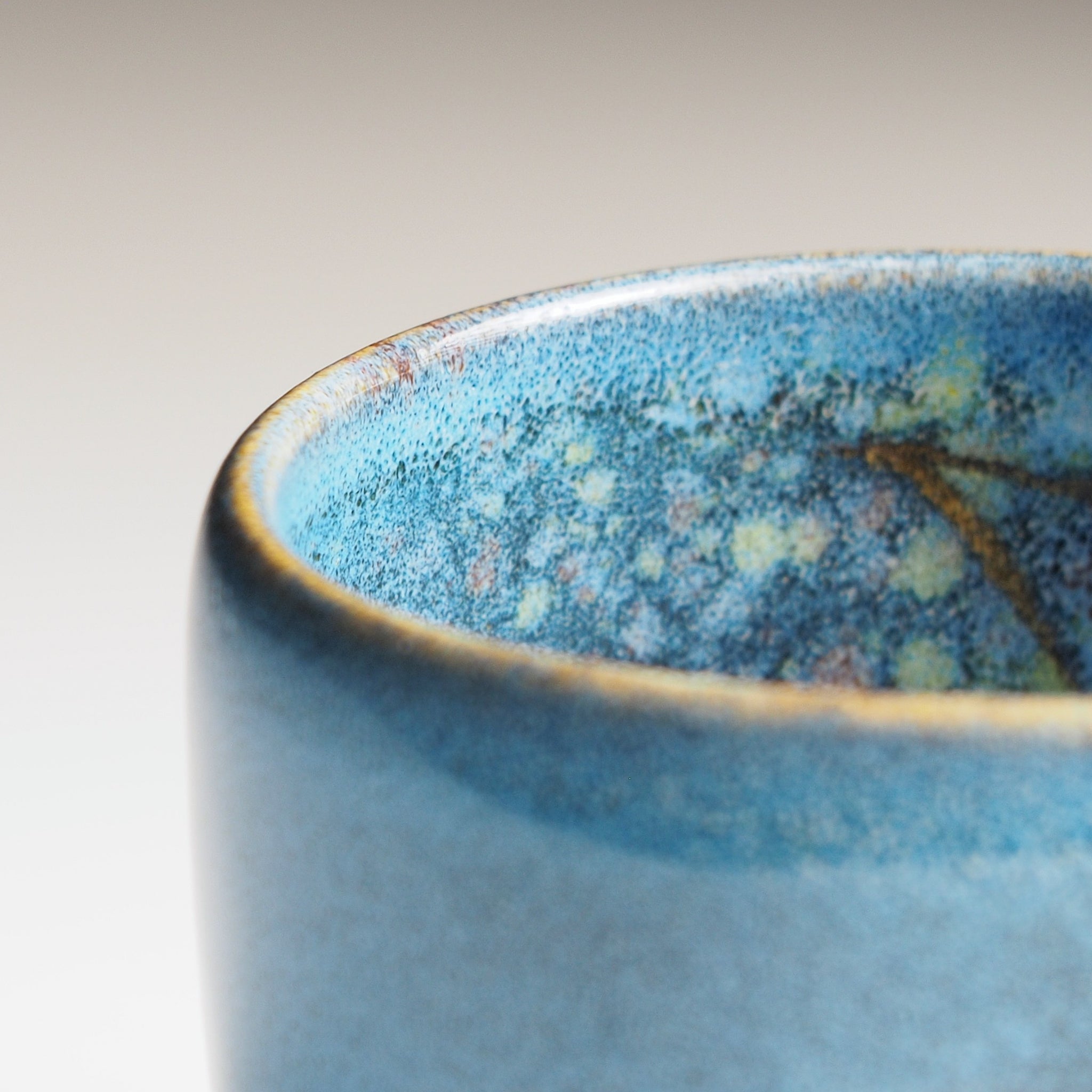 Close-up of the Maru Komorebi Yunomi blue teacup rim on a grey background.