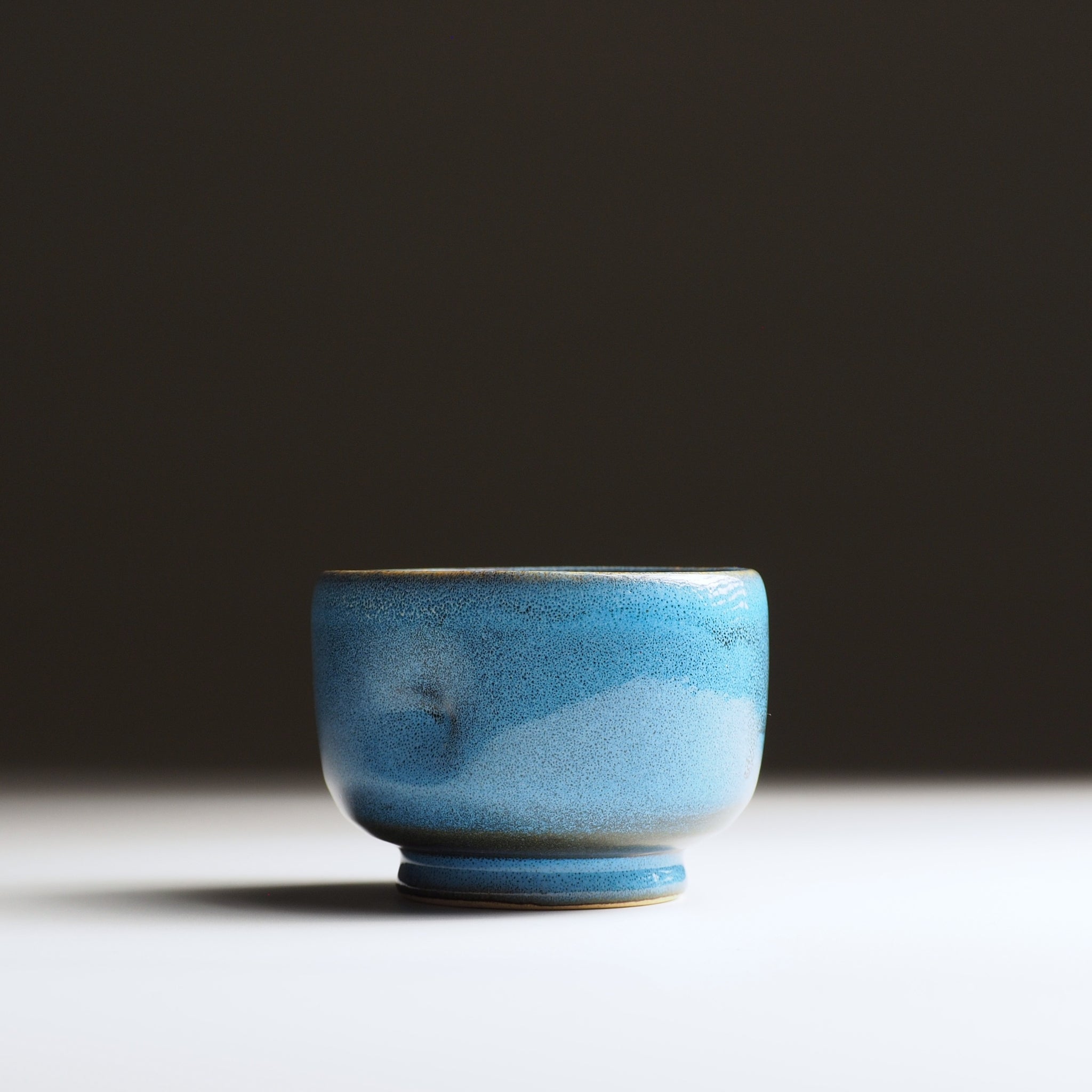 Maru Komorebi Yunomi blue teacup by master potter Kazuhiro Kojima. Front view on a faded background.