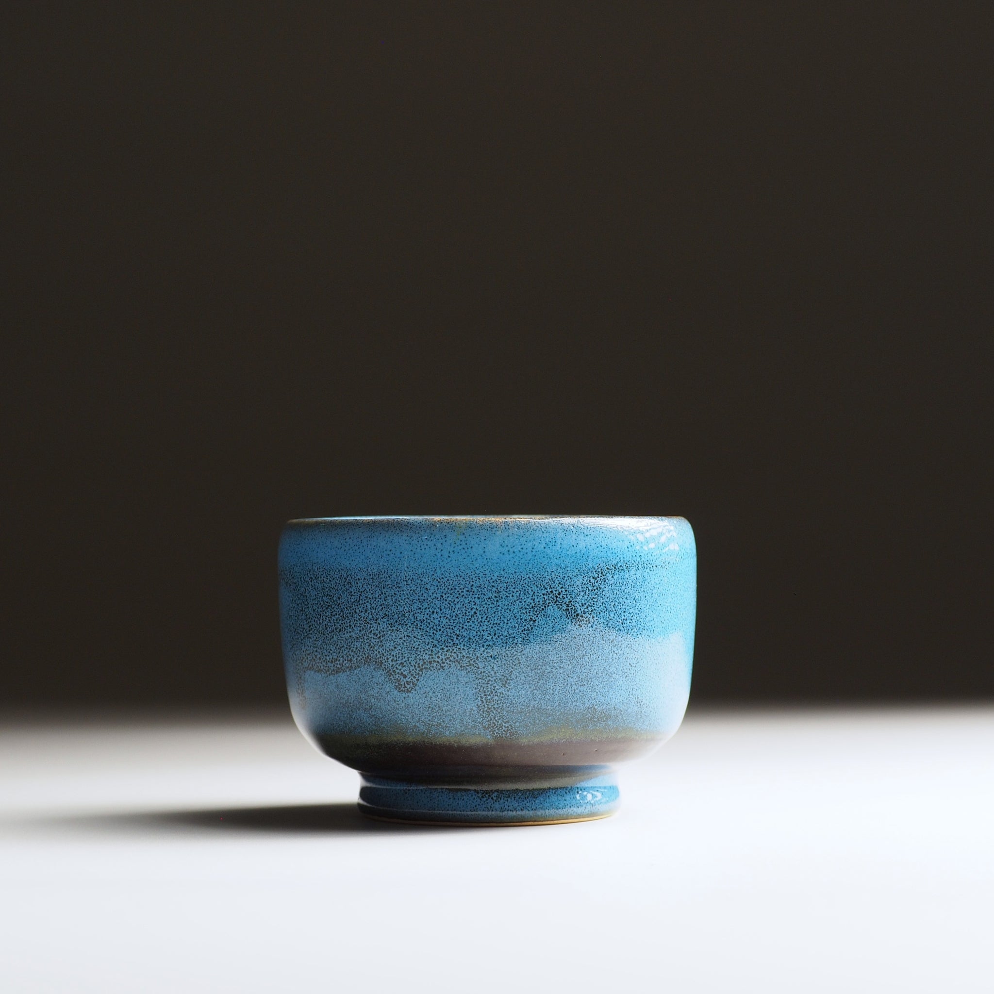 Maru Komorebi Yunomi teacup by K. Kojima in blue color, front view on a faded background.